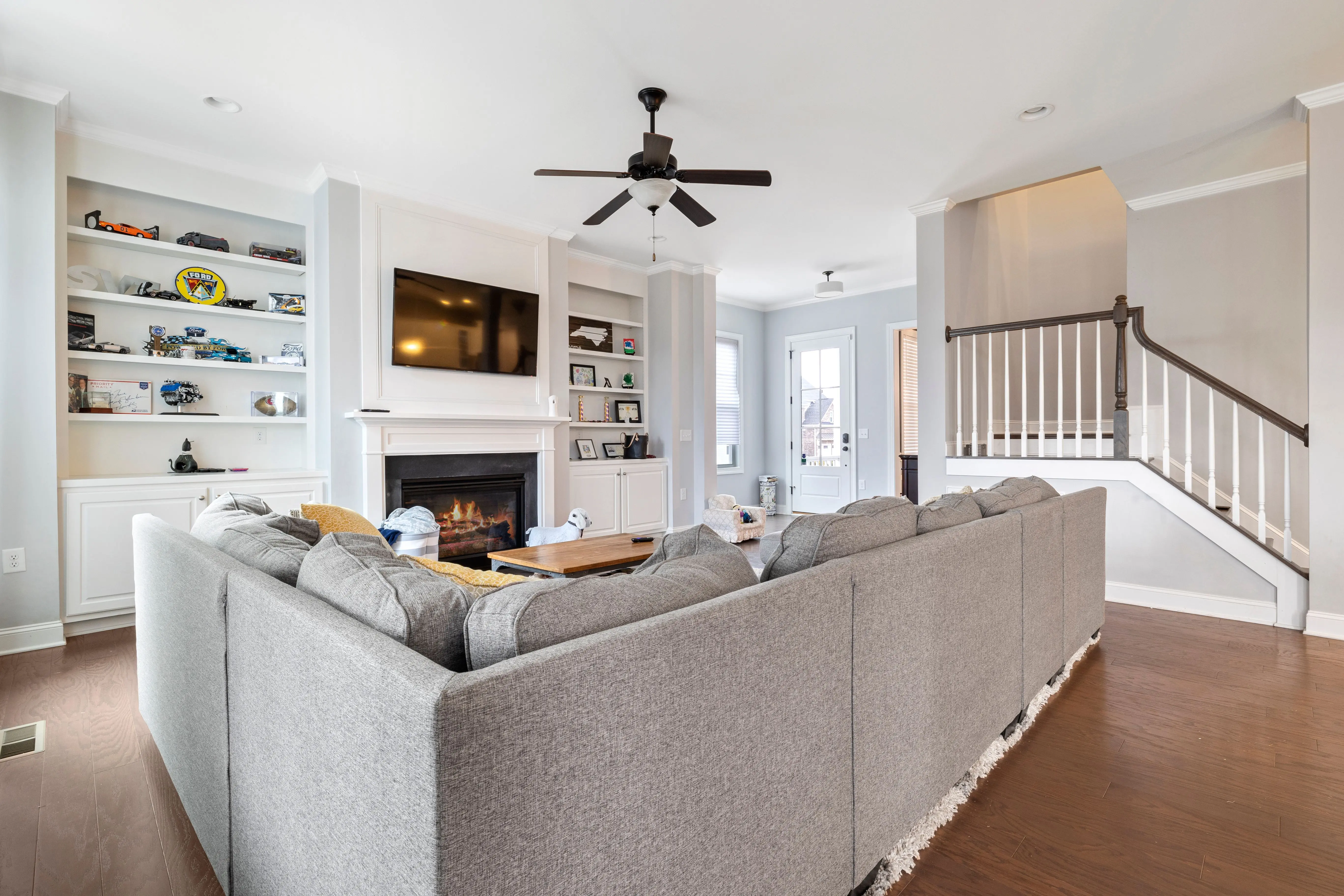 gray sectional Spacious modern living room with a cozy gray sectional, fireplace, and open shelving.