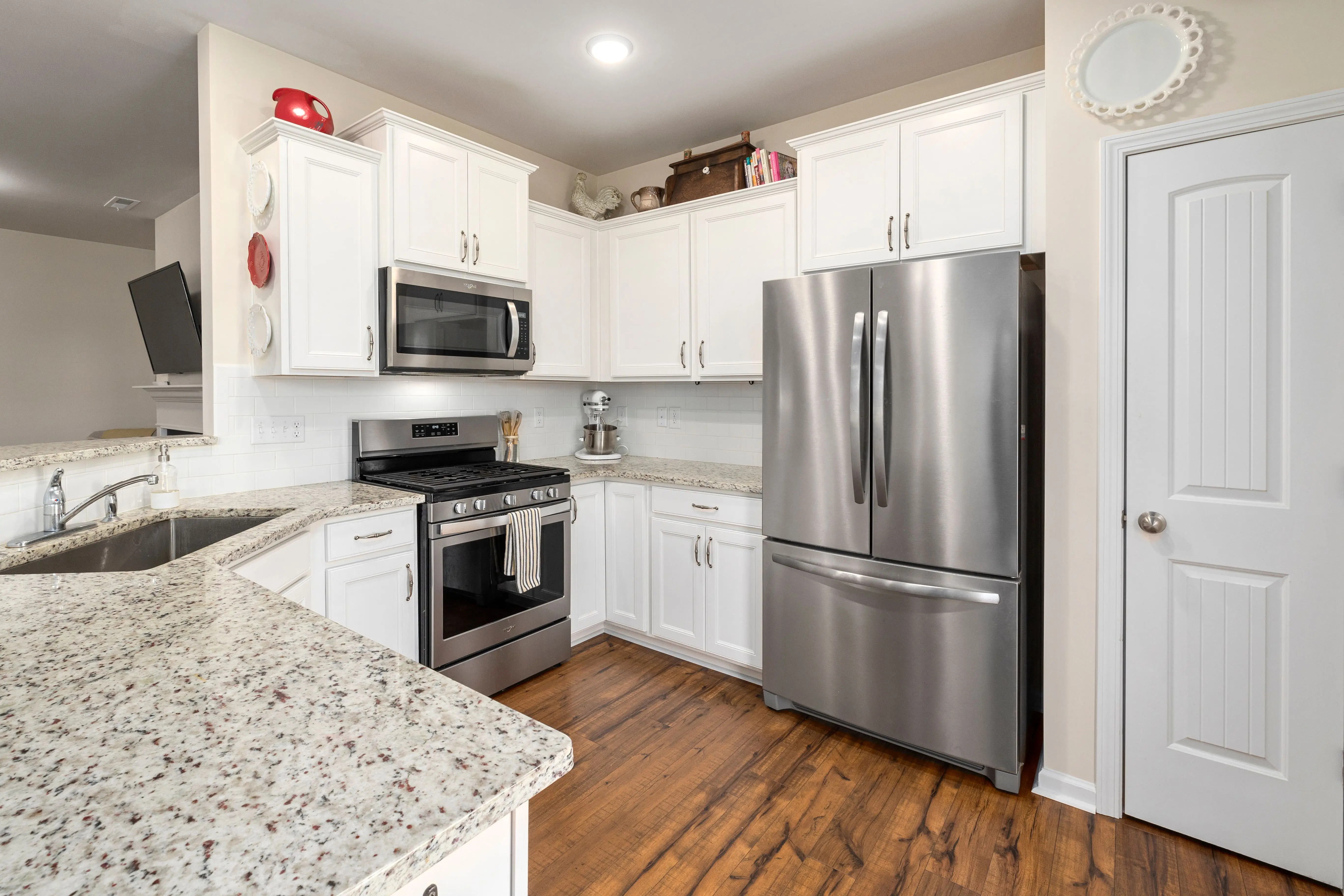 corner cabinets for kitchen Bright modern kitchen featuring white cabinets and stainless steel appliances, including a refrigerator and stove.