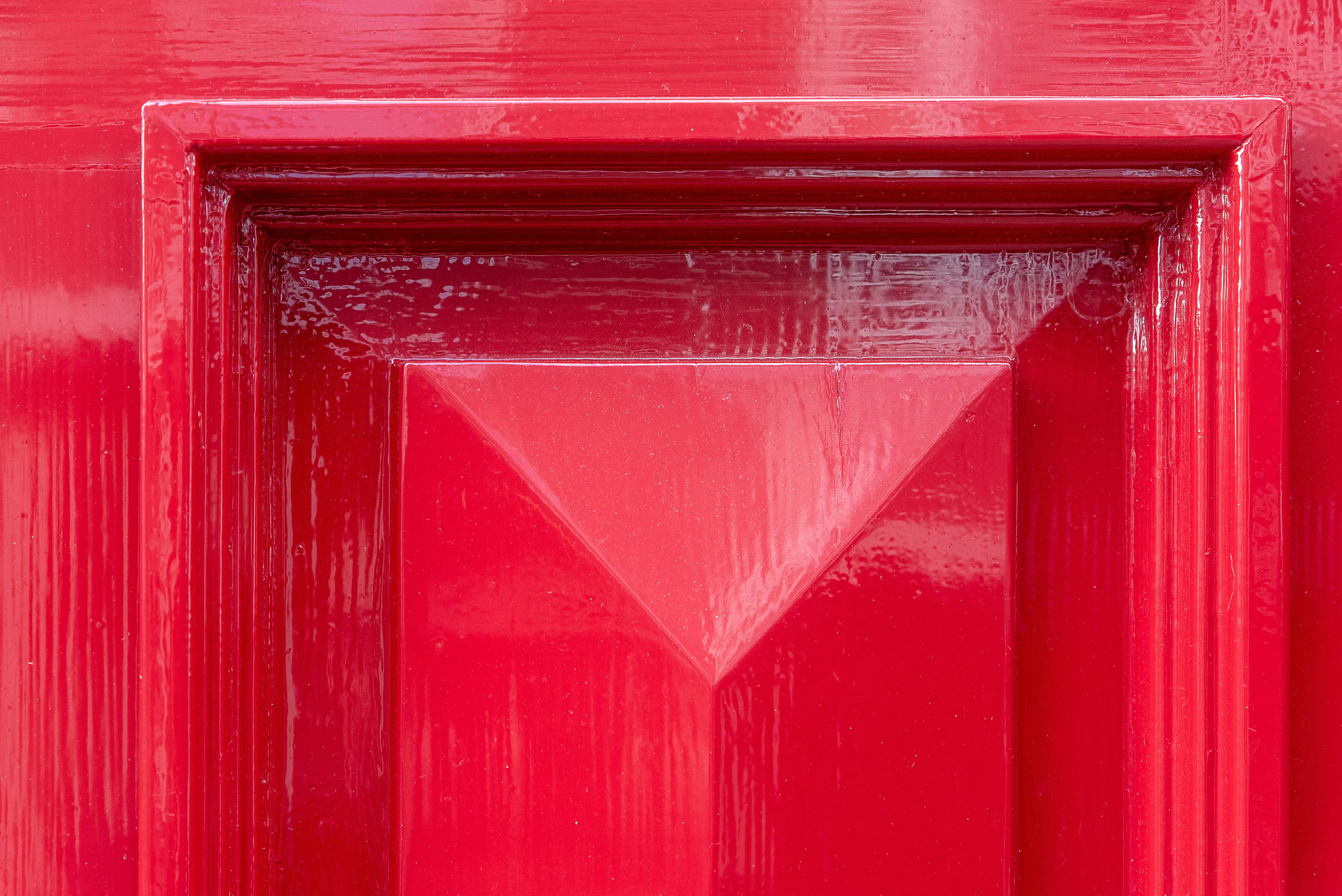 why make trims and doors satin paint Close-up of a vibrant red door featuring a geometric design, perfect for architecture and design themes.