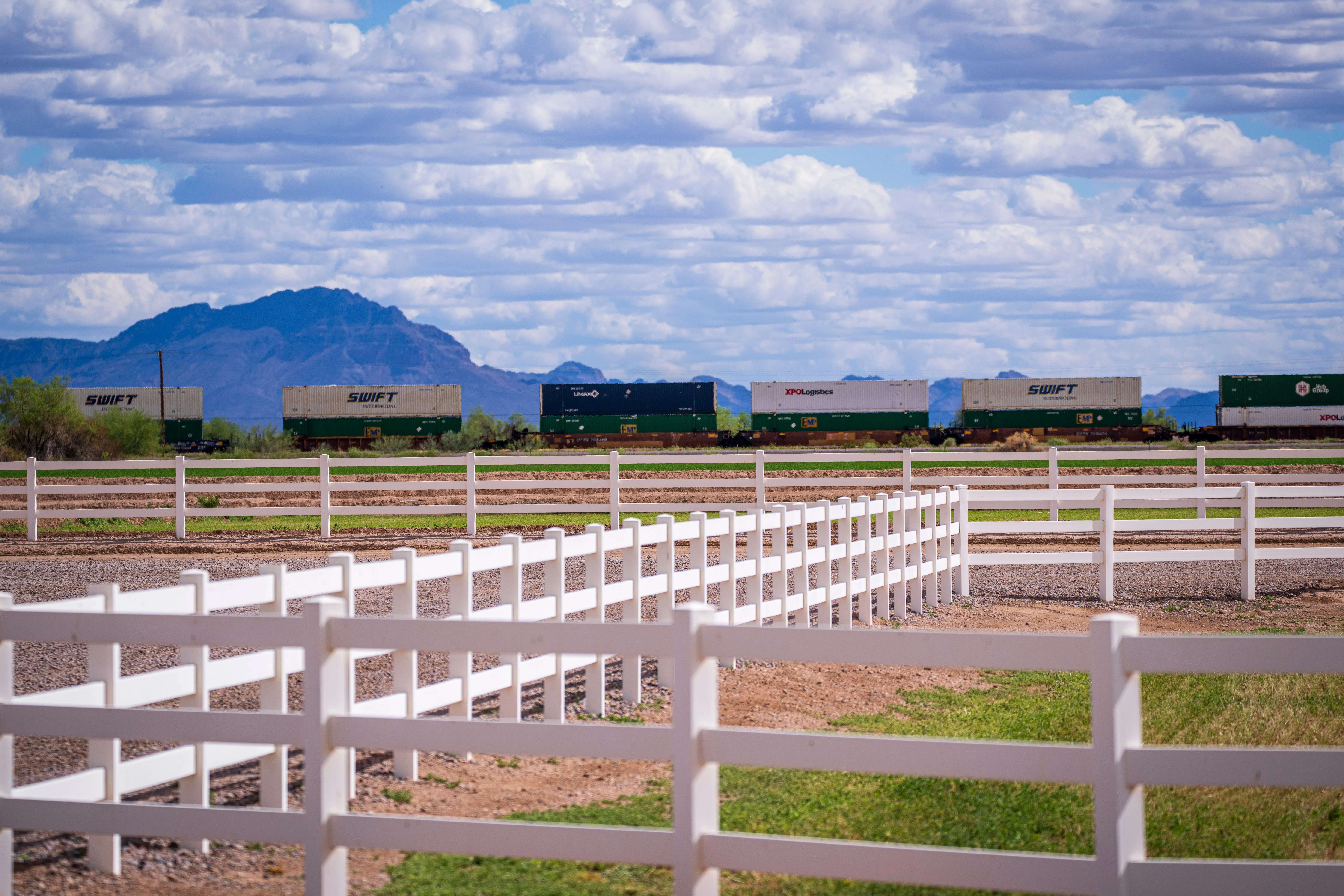 wood fence styles Vibrant landscape showcasing trains, white fences, and Arizona mountains in the distance.