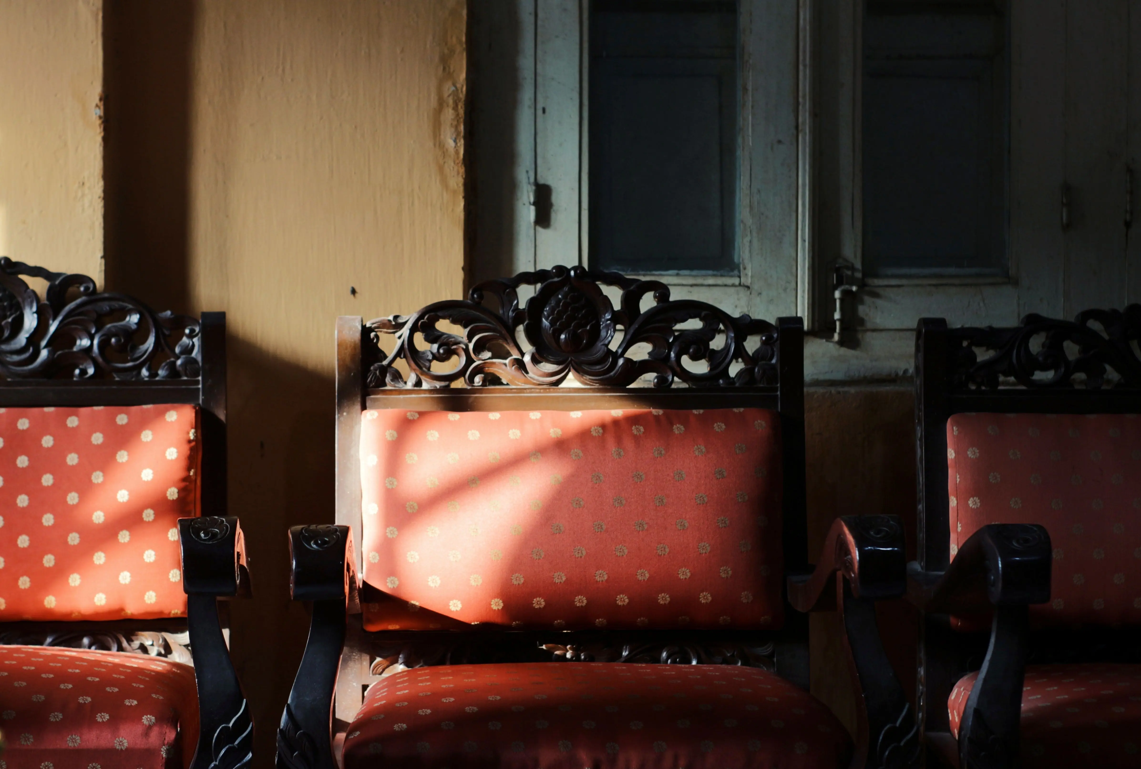 living room chairs set of 2 Elegant carved wooden armchairs in a sunlit room highlight traditional Indonesian craftsmanship.