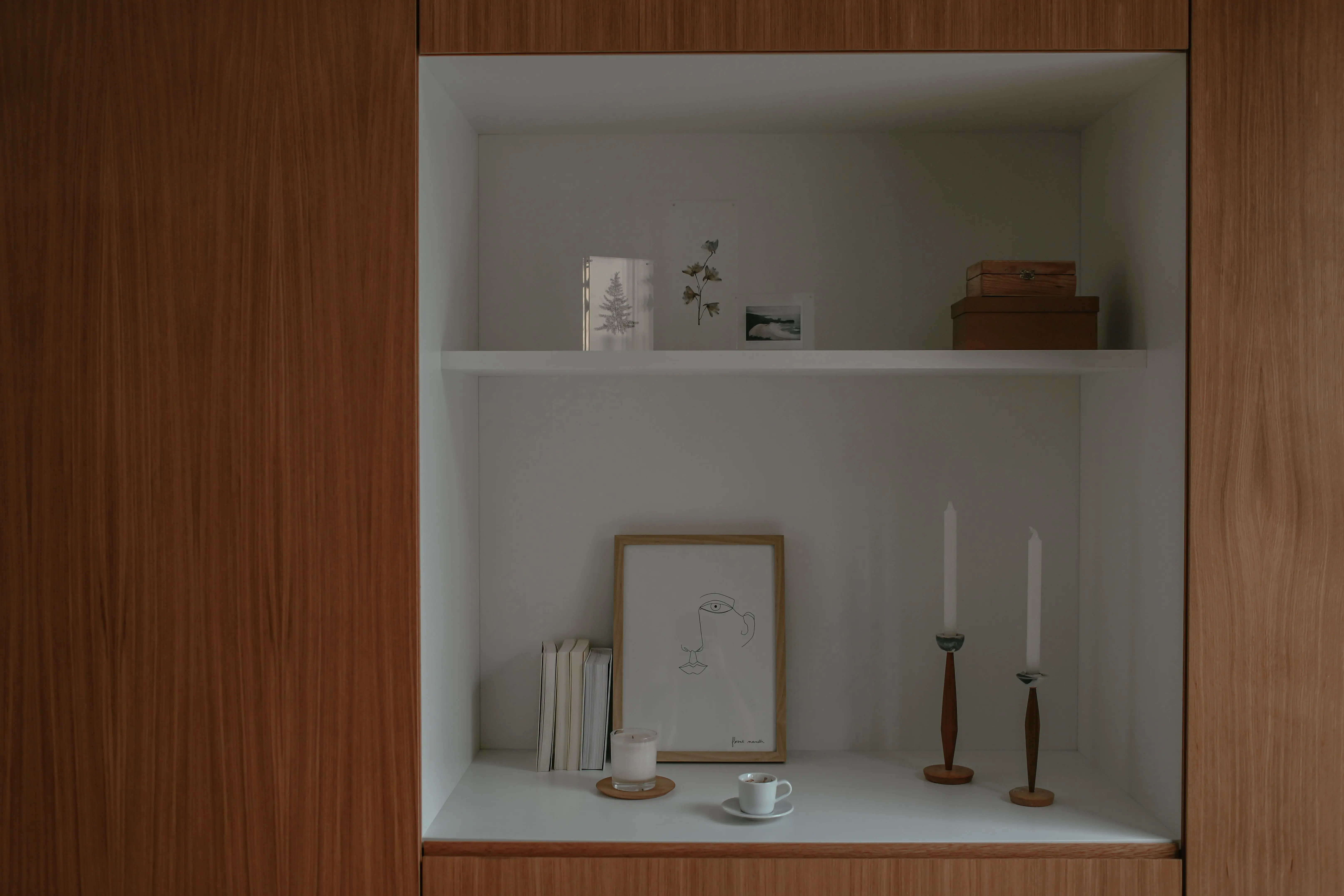 tall candle holders Elegant minimalist shelf with books, candles, and wooden decor items.