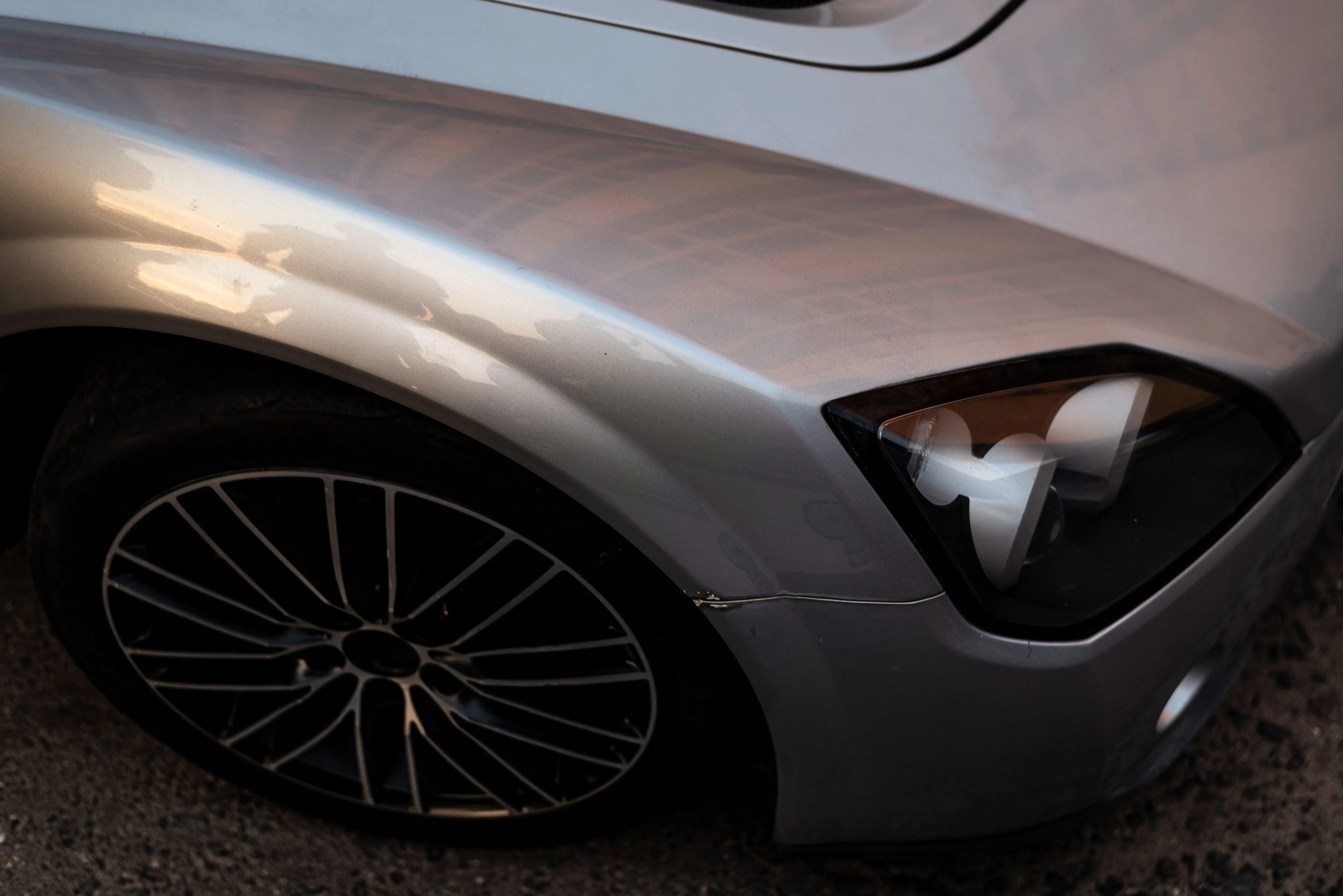 paint chip repair Detailed view of a silver car's headlight and wheel with a smooth metallic finish.