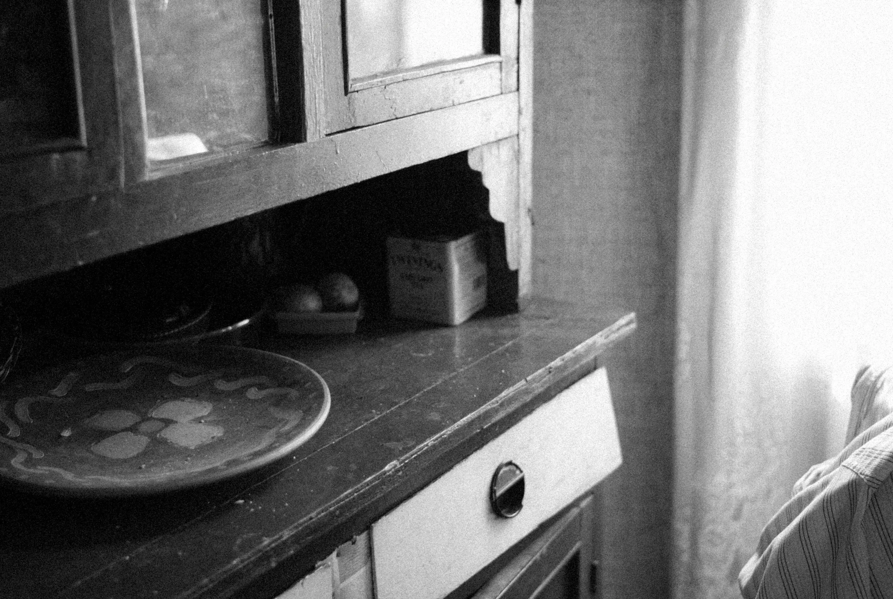 cherry kitchen cabinets A black and white photo of a rustic wooden cabinet with a decorative dish on top.