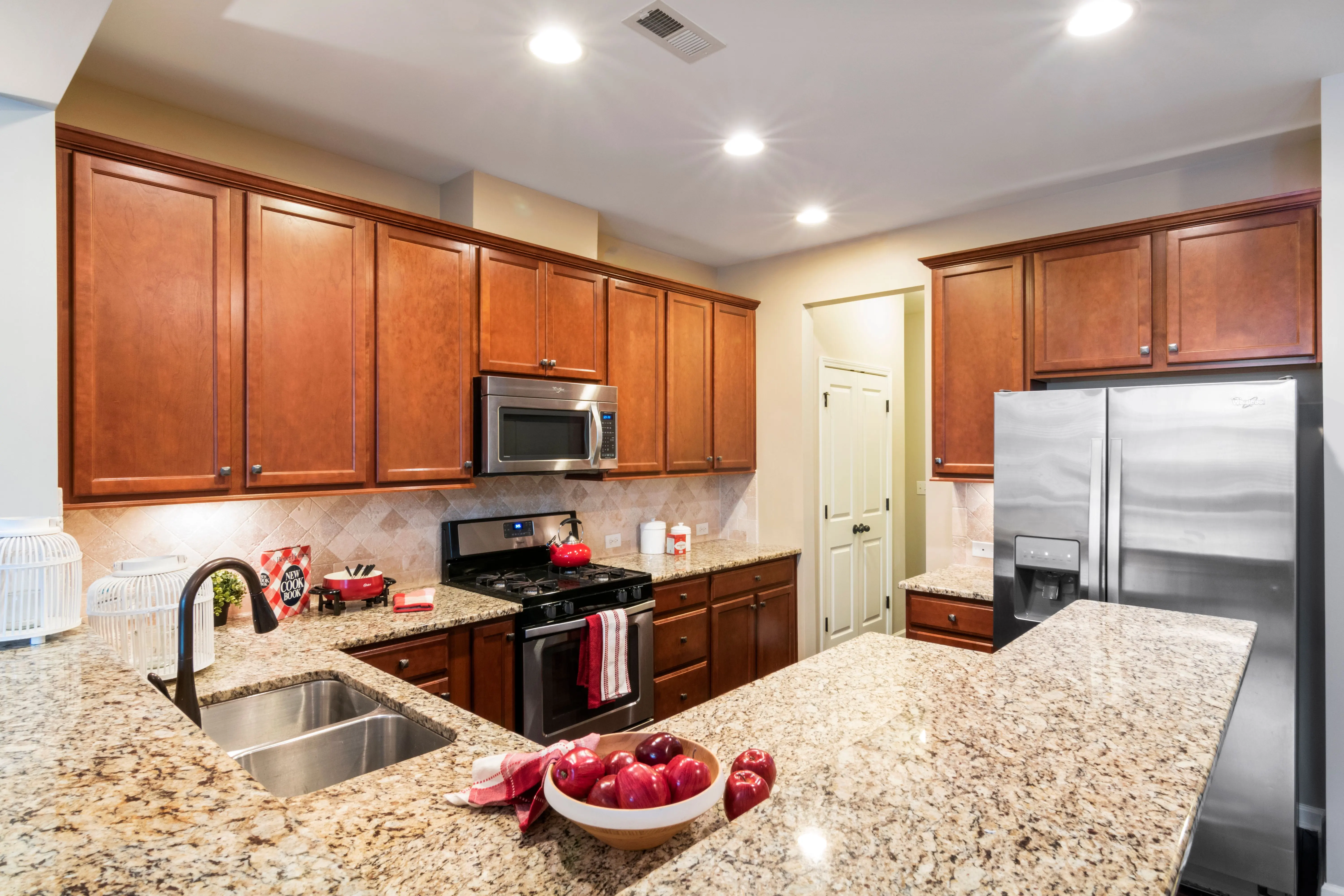 cherry kitchen cabinets A spacious modern kitchen featuring granite countertops and stainless steel appliances.