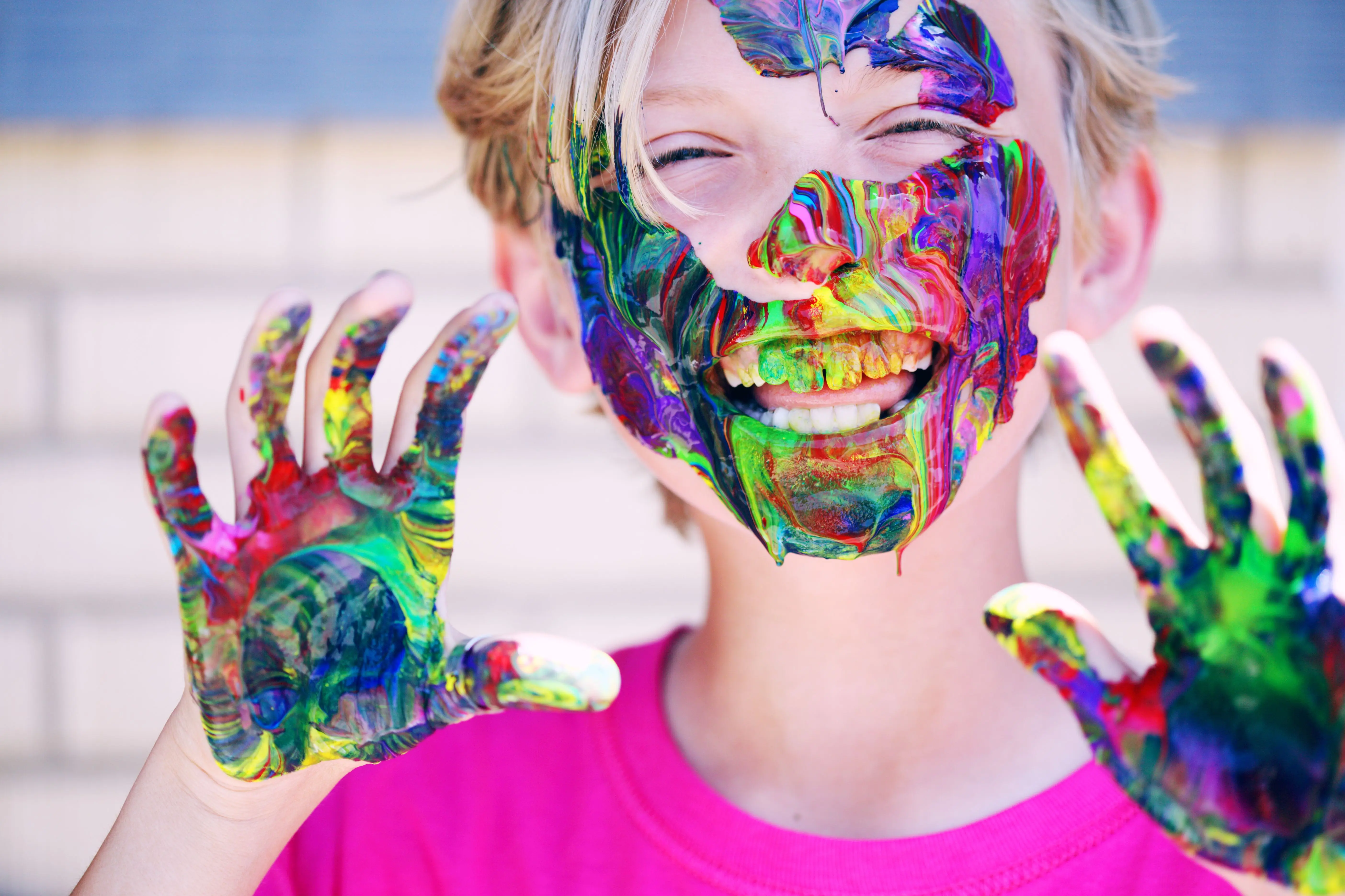 kids painting A joyful child with vibrant face paint and hands, expressing happiness and creativity.