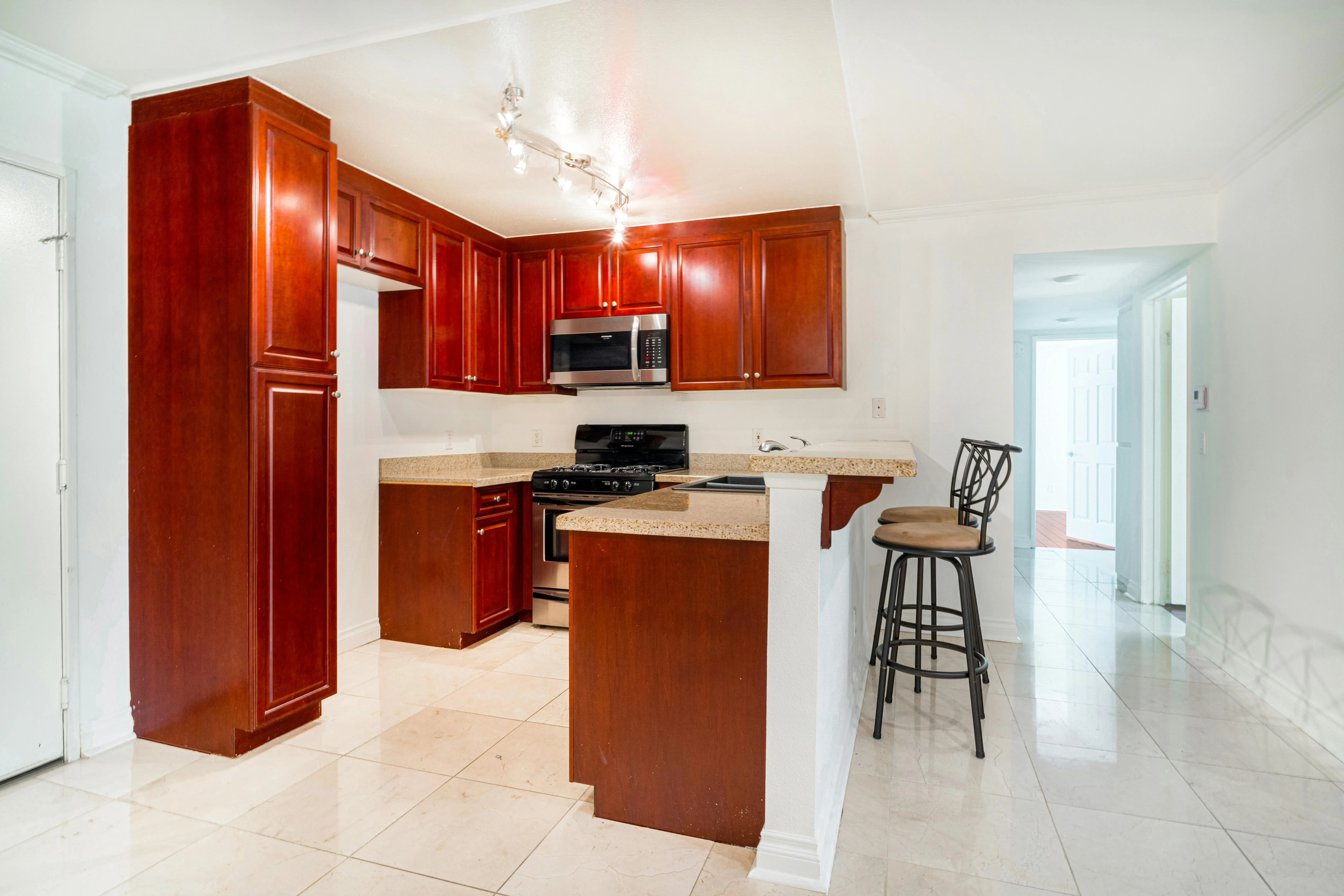 cherry kitchen cabinets Sleek kitchen interior with cherry wood cabinets, granite countertops, and stainless steel appliances.