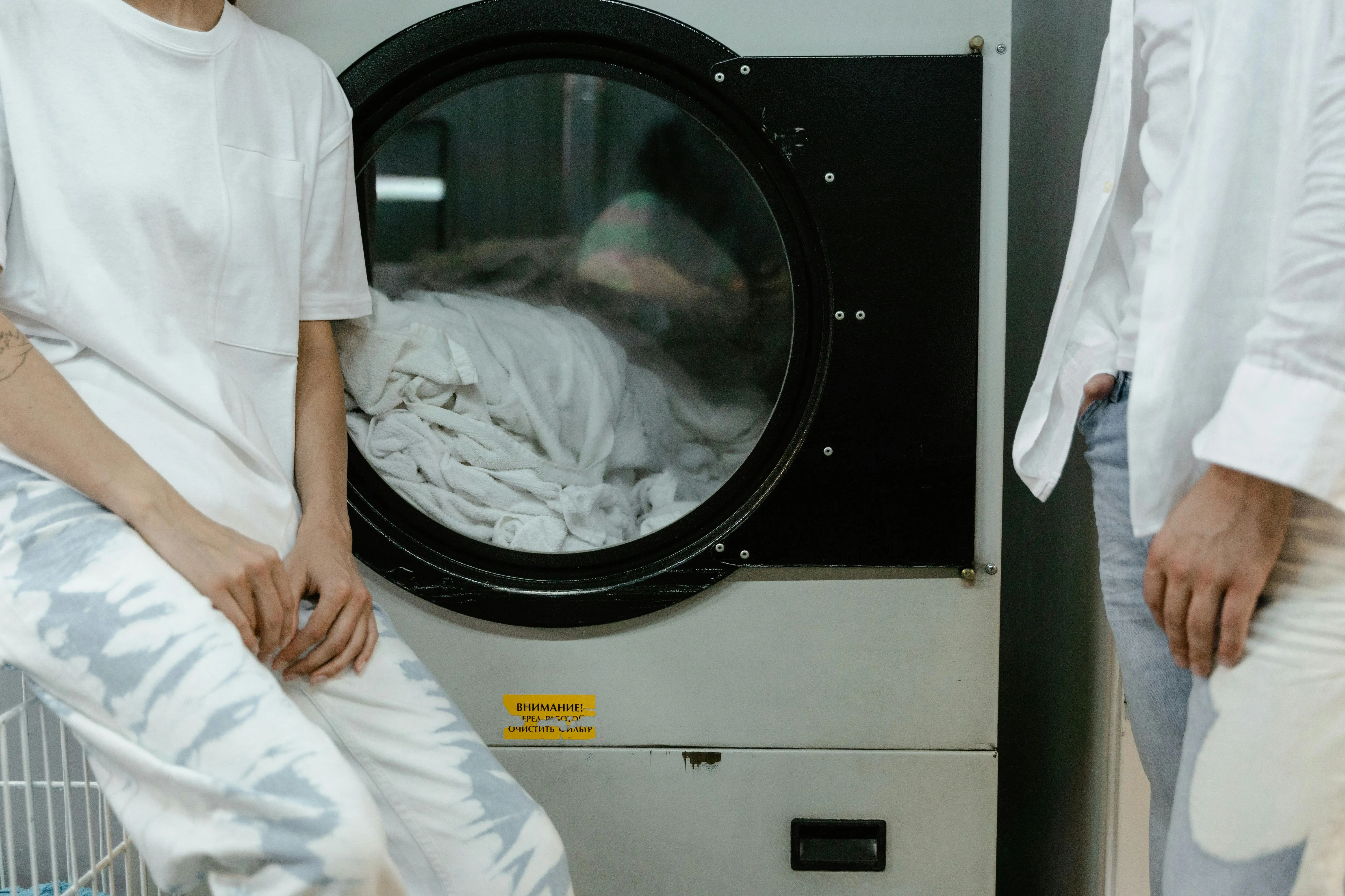 dryer not spinning Adults in white clothes using a washing machine in a laundry facility.