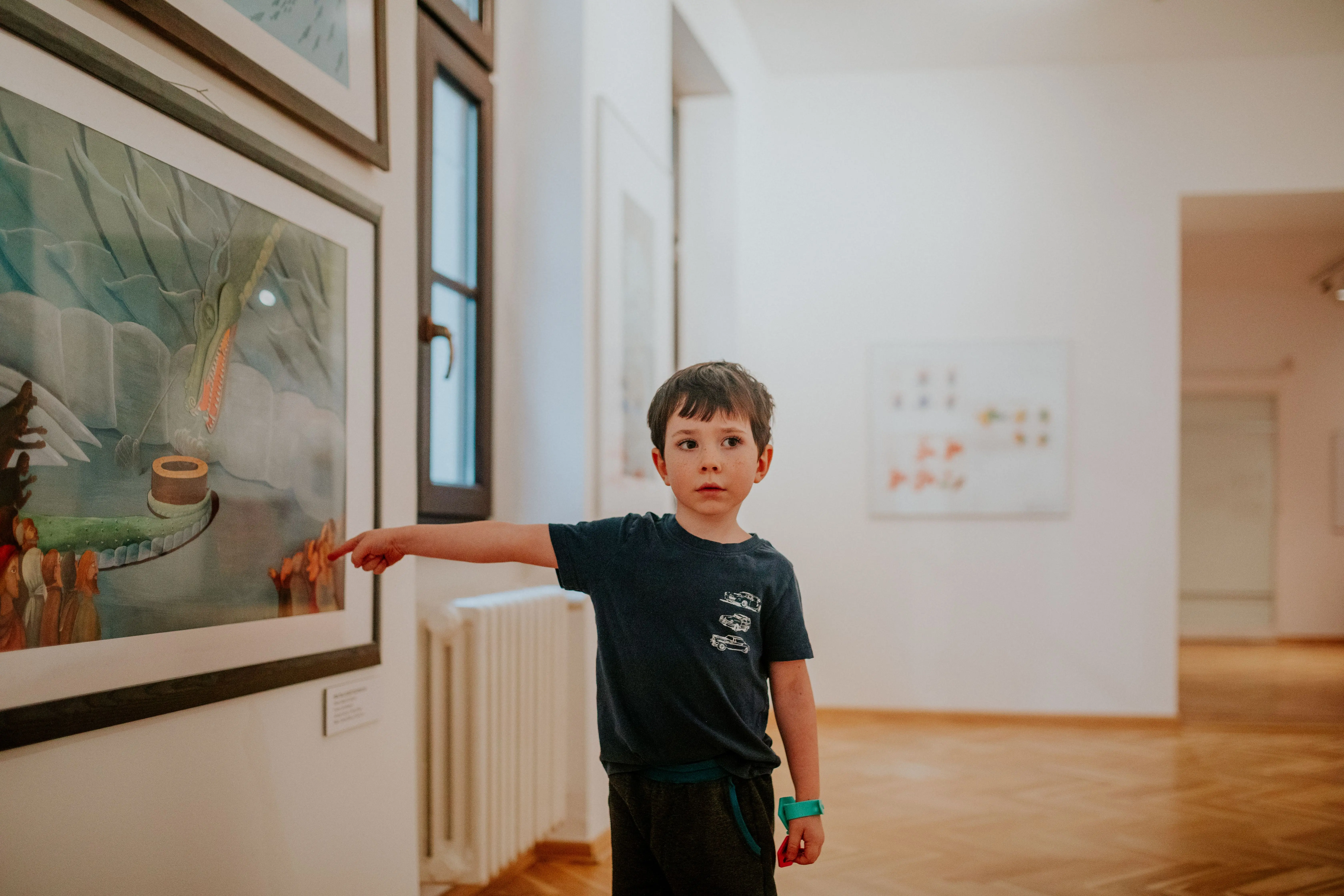 kids painting A young boy pointing at artwork in a modern art gallery, showing interest and curiosity.