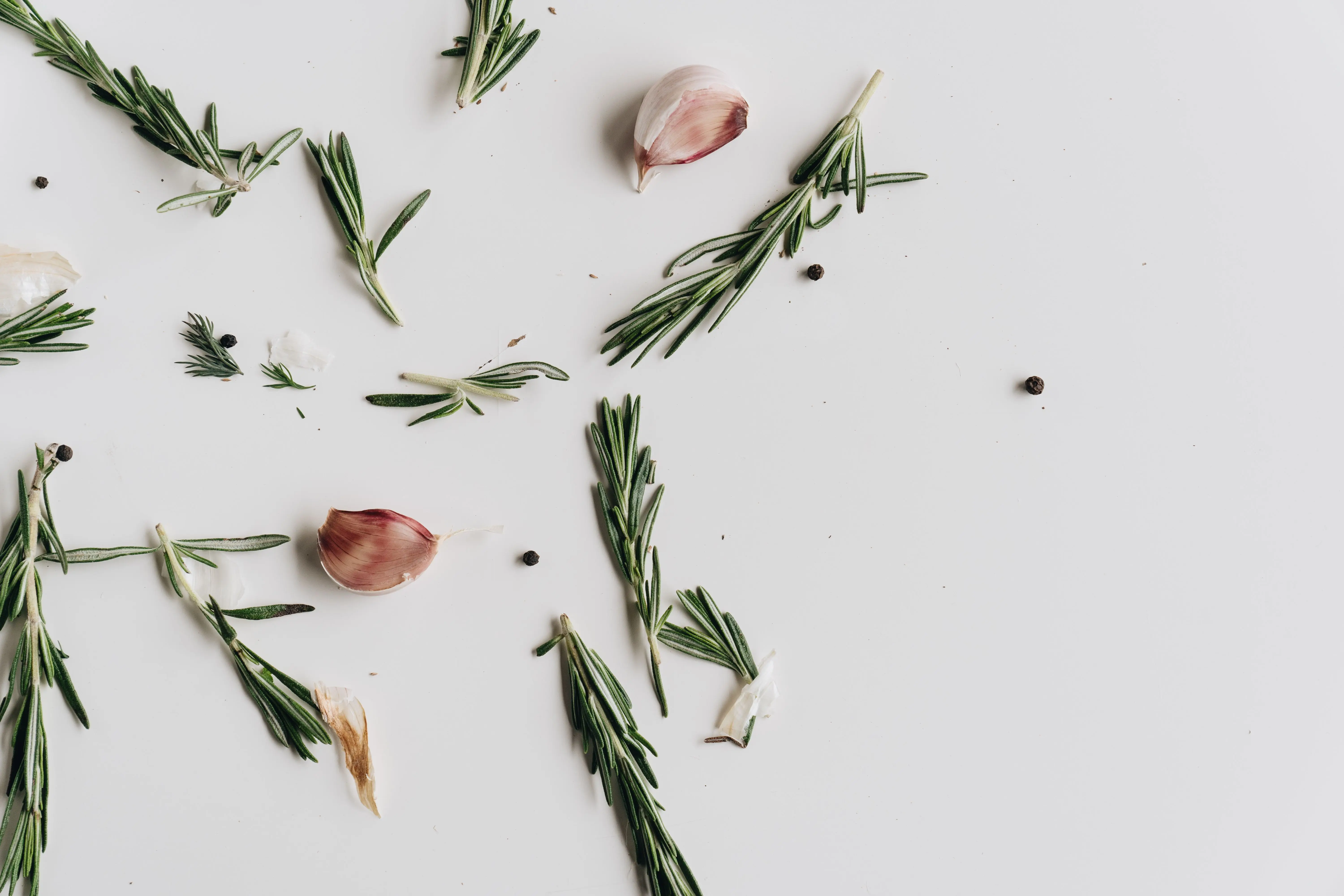 thyme seeds Aromatic rosemary, garlic, and peppercorns artfully arranged on a white surface.