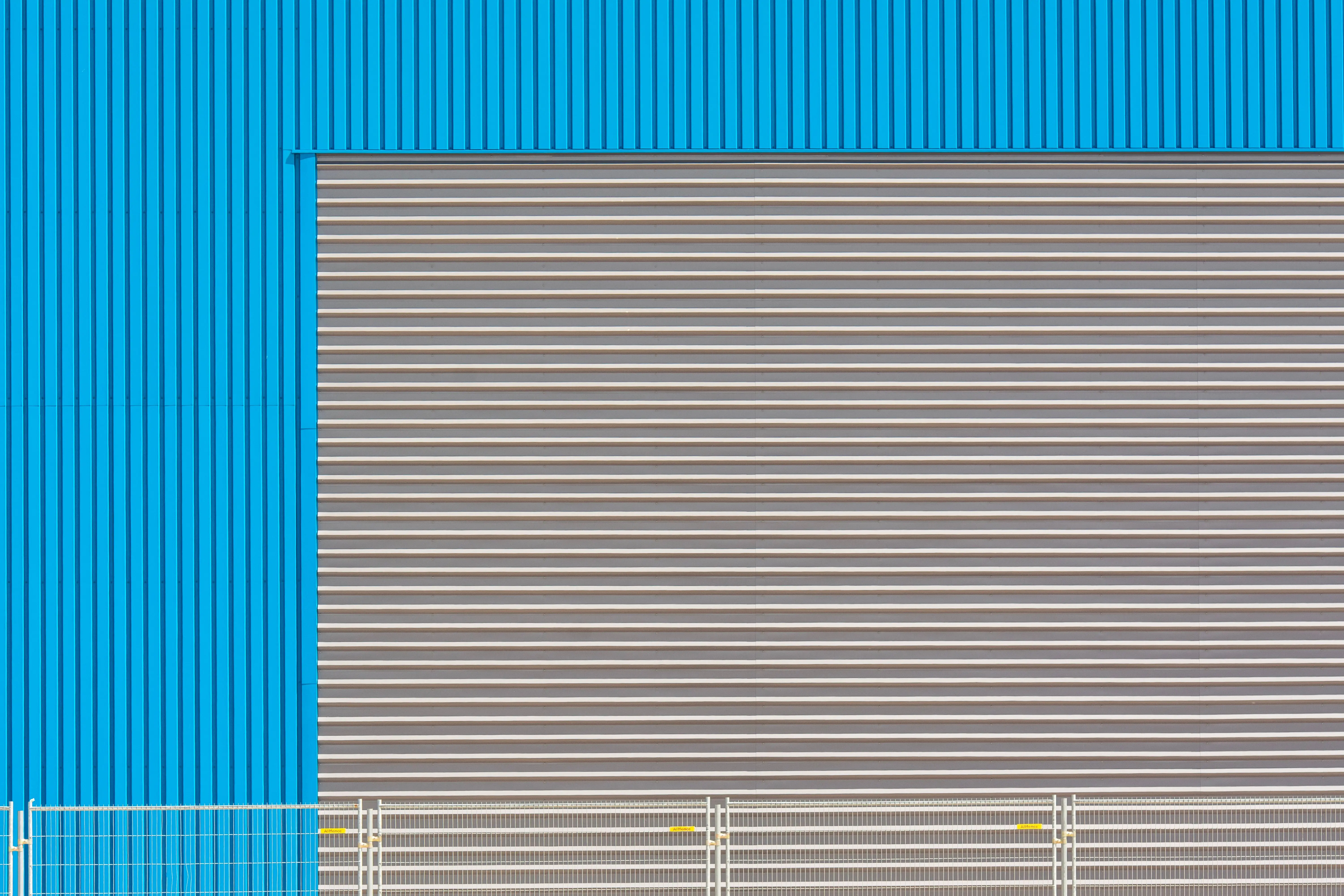black garage door Blue industrial building facade with shutter door, showcasing modern architecture.