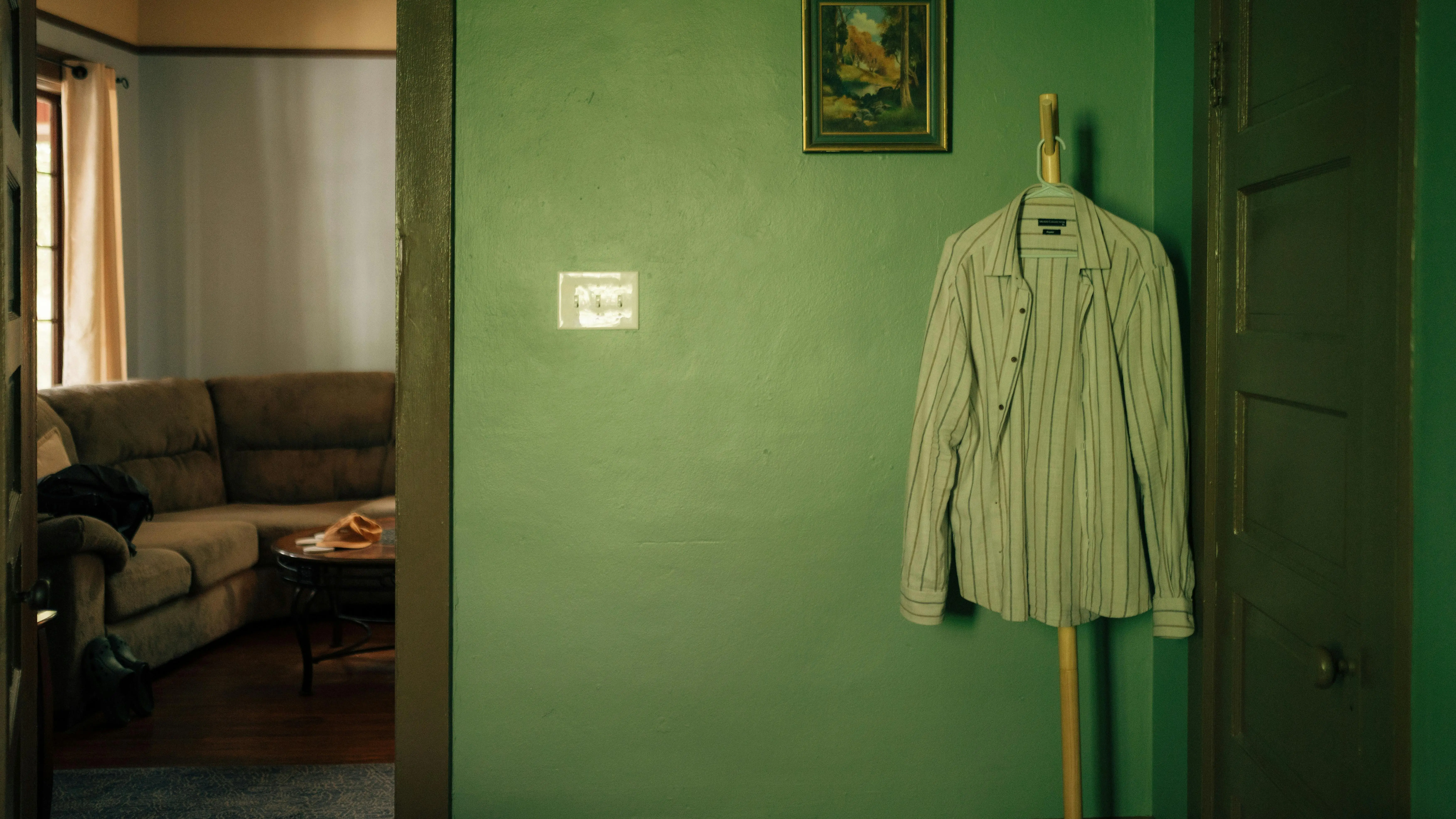 light green paint A minimalist interior shot featuring a striped shirt hanging on a green wall in Gainesville, FL.