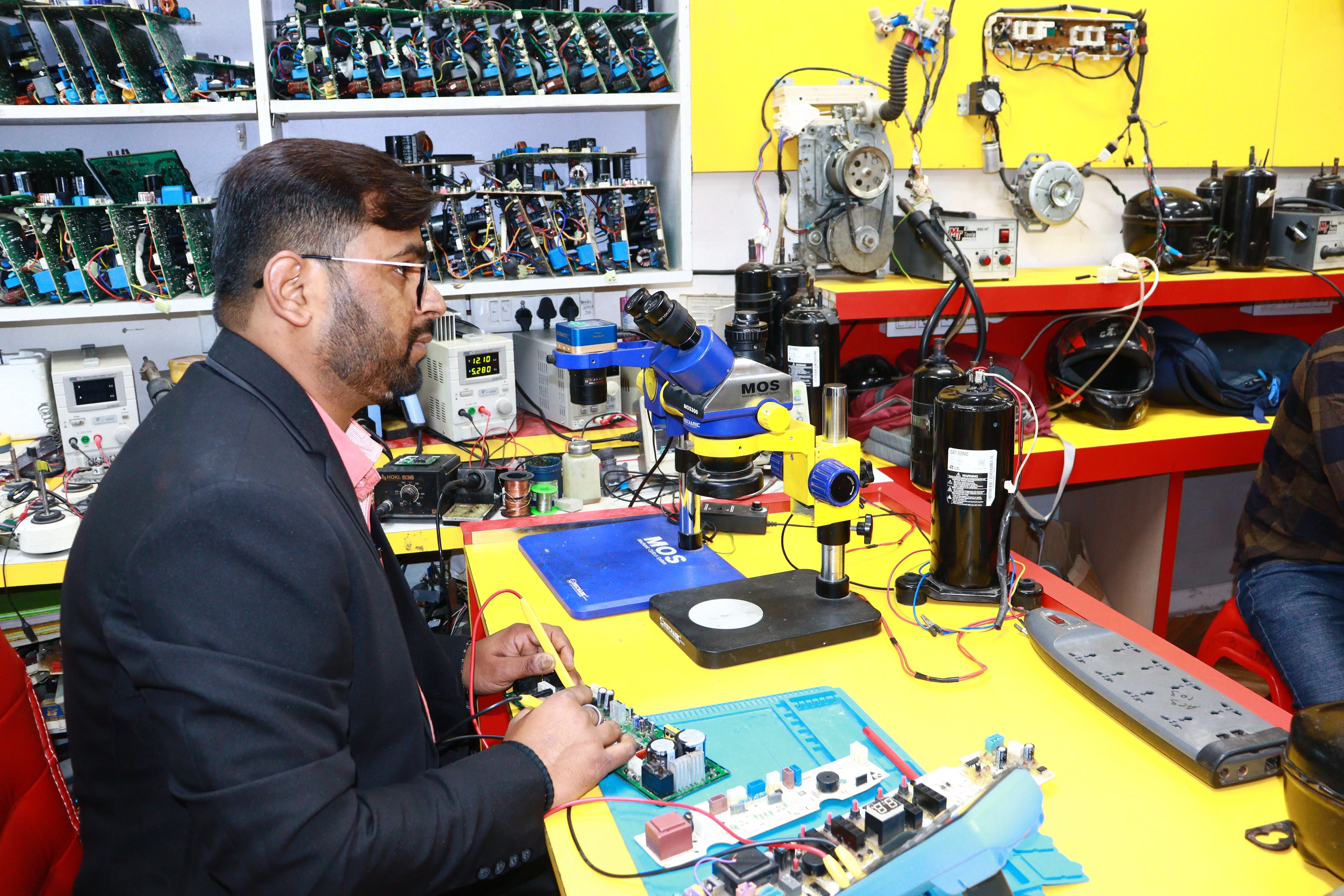 dryer not spinning A man in Delhi working in an electronics lab with tools and components.
