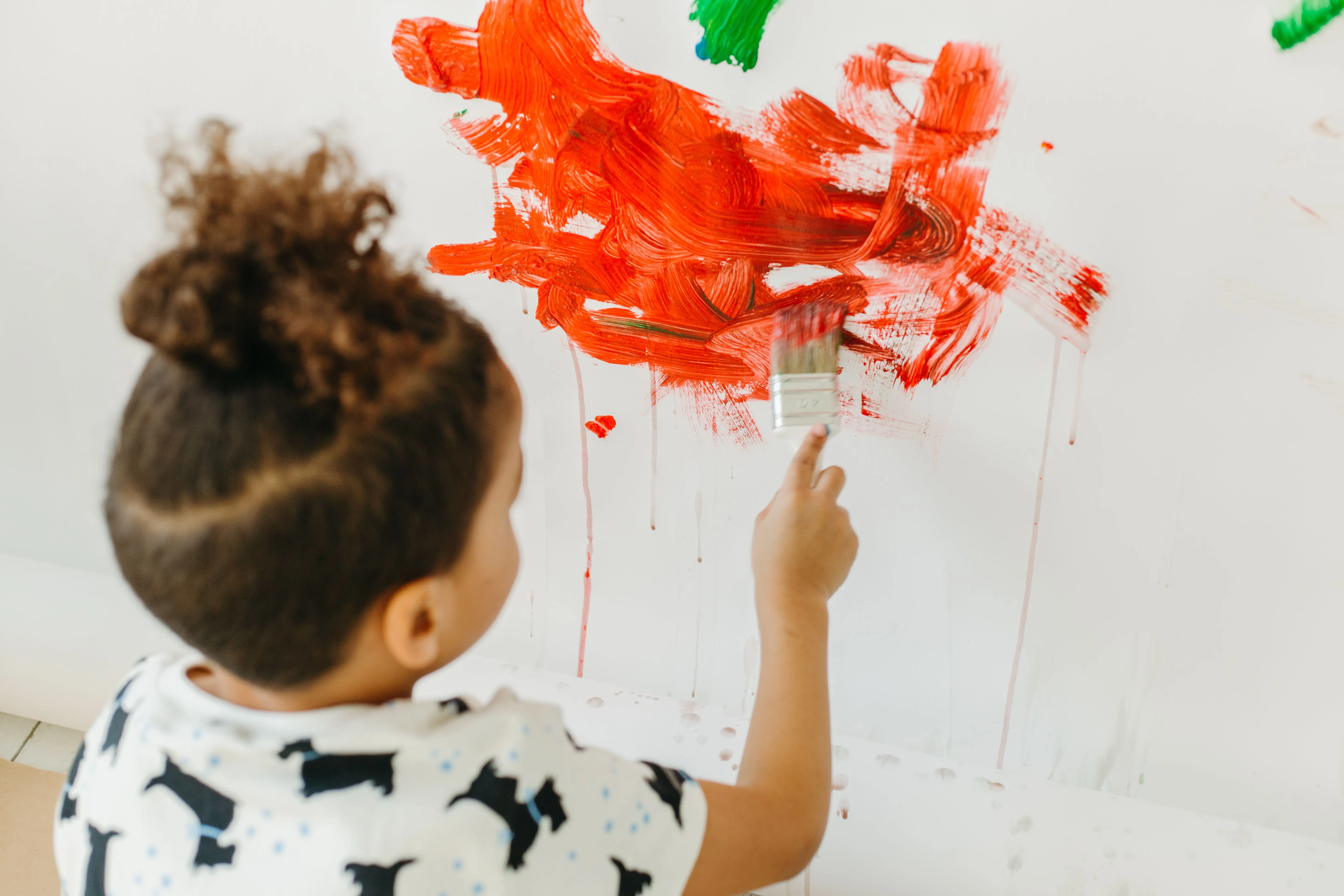 kids painting Young boy painting with vibrant colors on a white wall, expressing creativity and imagination.