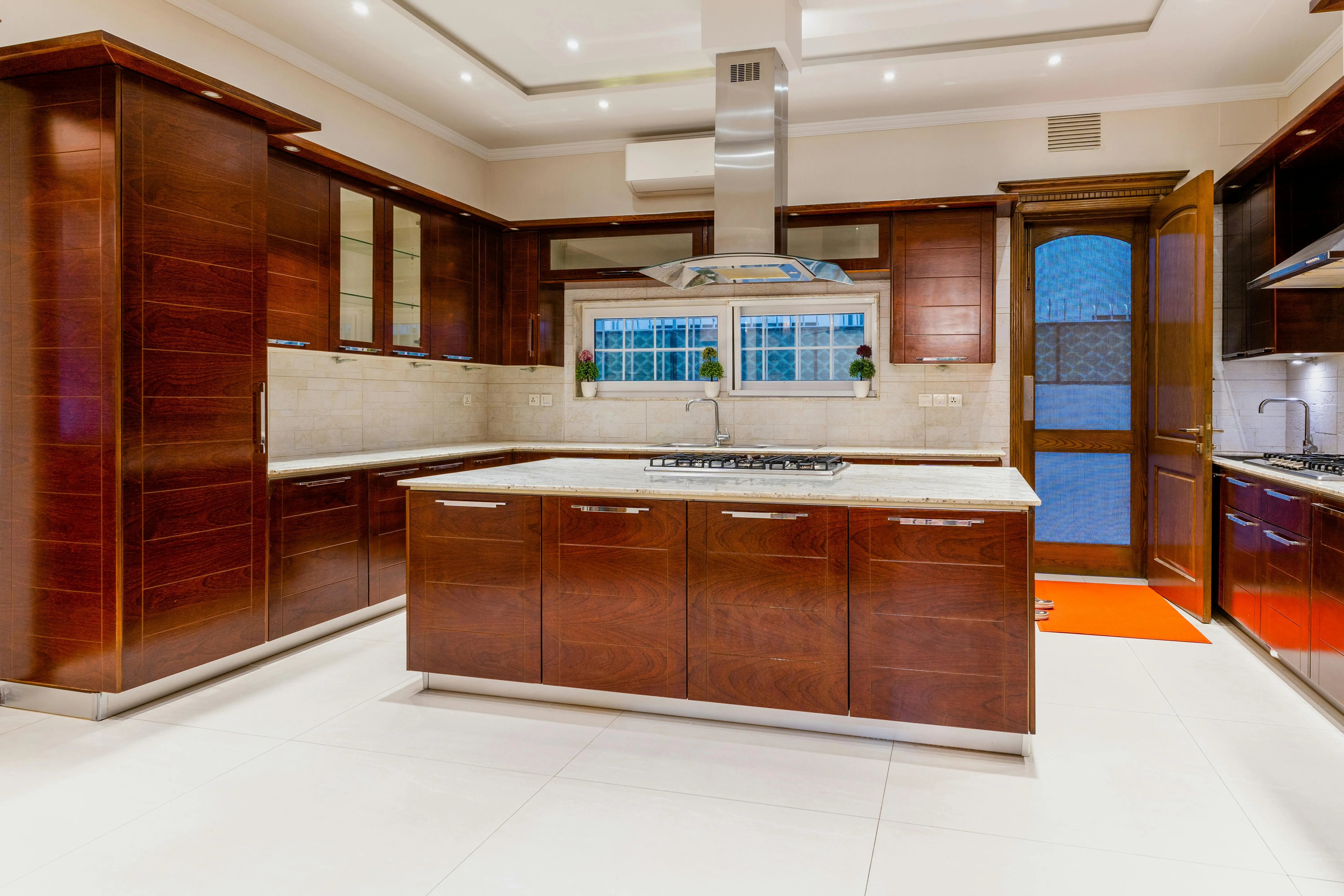 cherry kitchen cabinets Modern kitchen with dark wood cabinets and marble countertops, emphasizing elegant interior design.
