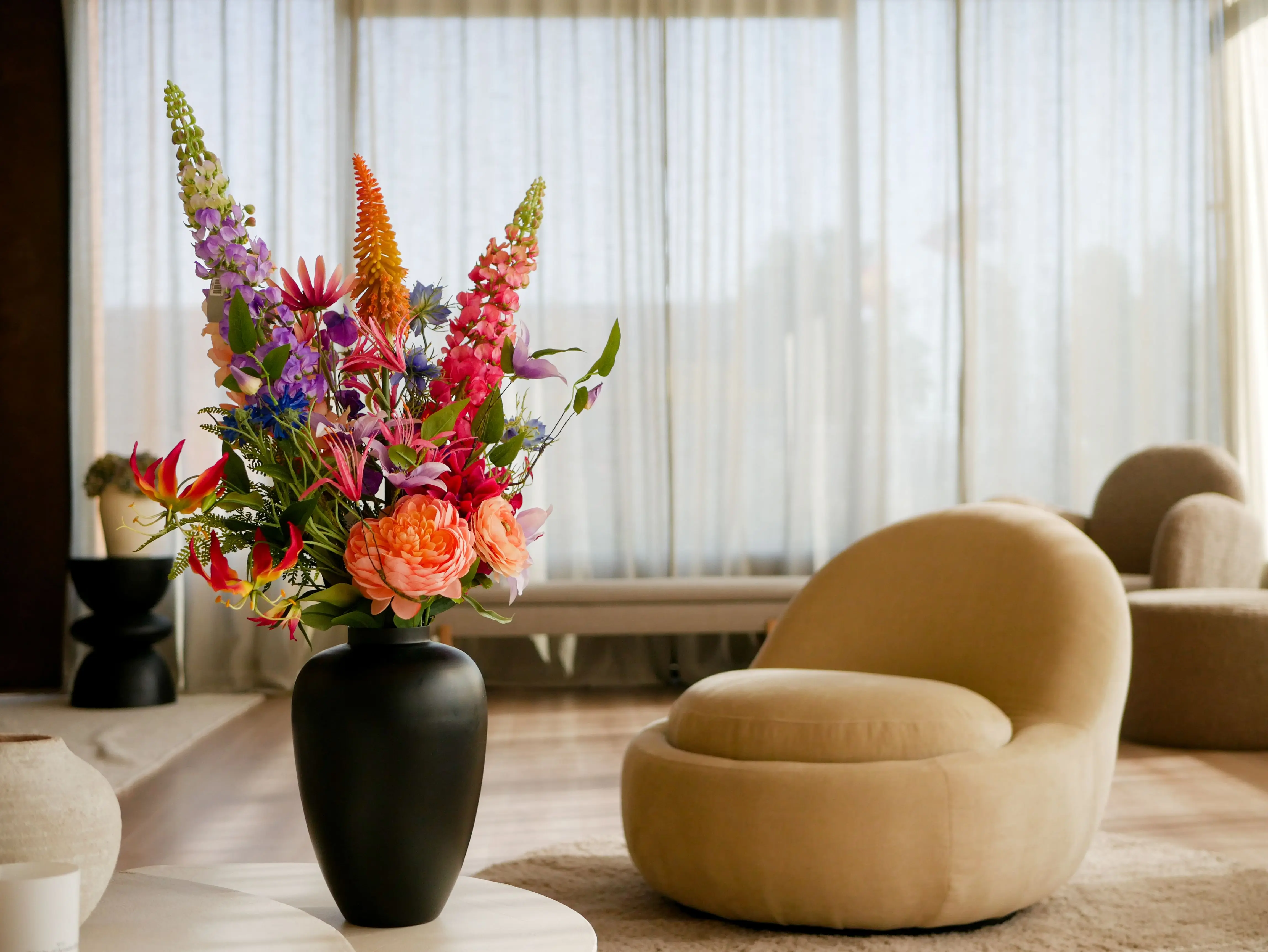 small living room ideas with tv A stylish living room featuring a vibrant flower arrangement in a sleek black vase, creating a sophisticated interior decor.