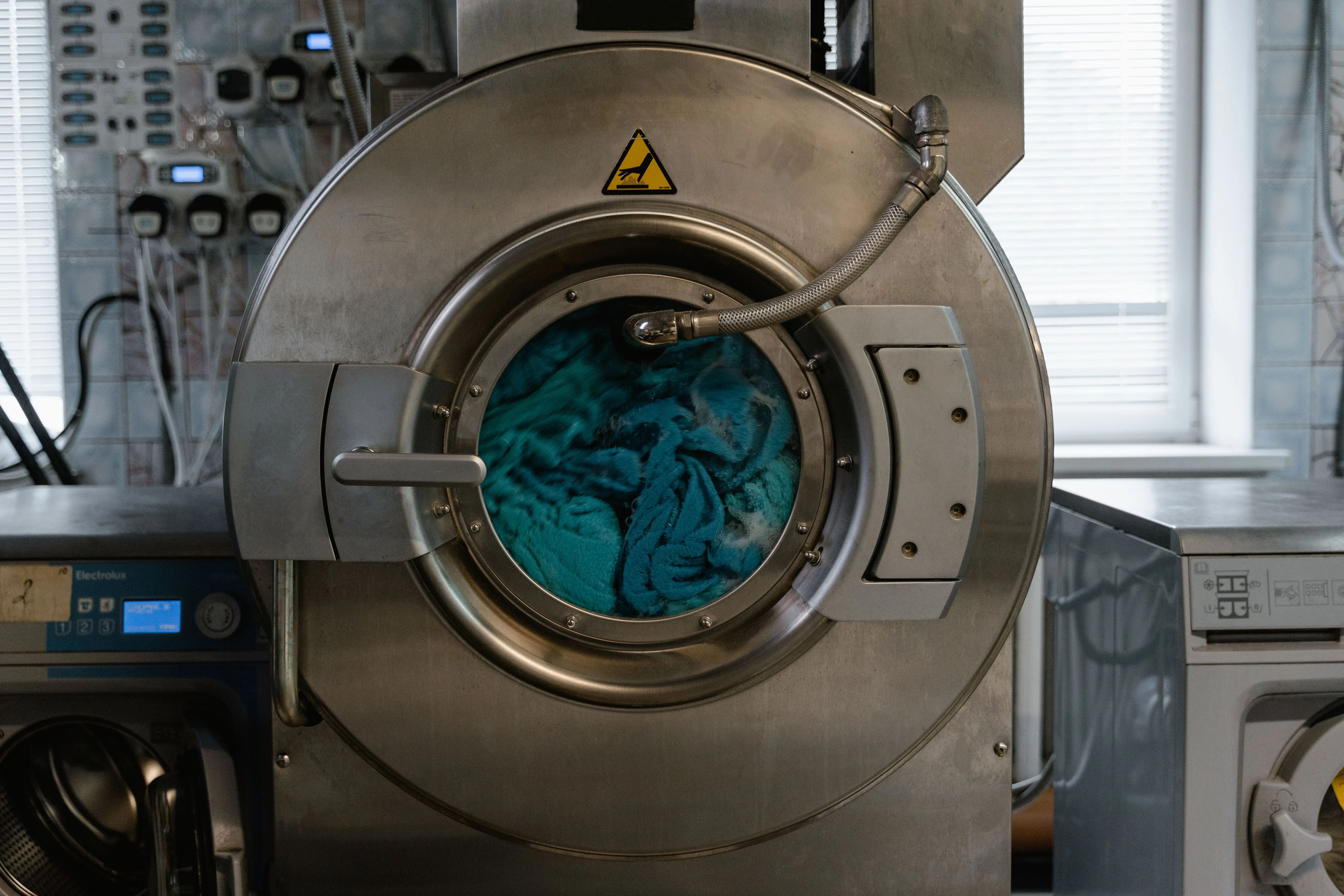 heavy duty washer Large industrial washing machine with blue fabrics in a laundry facility.