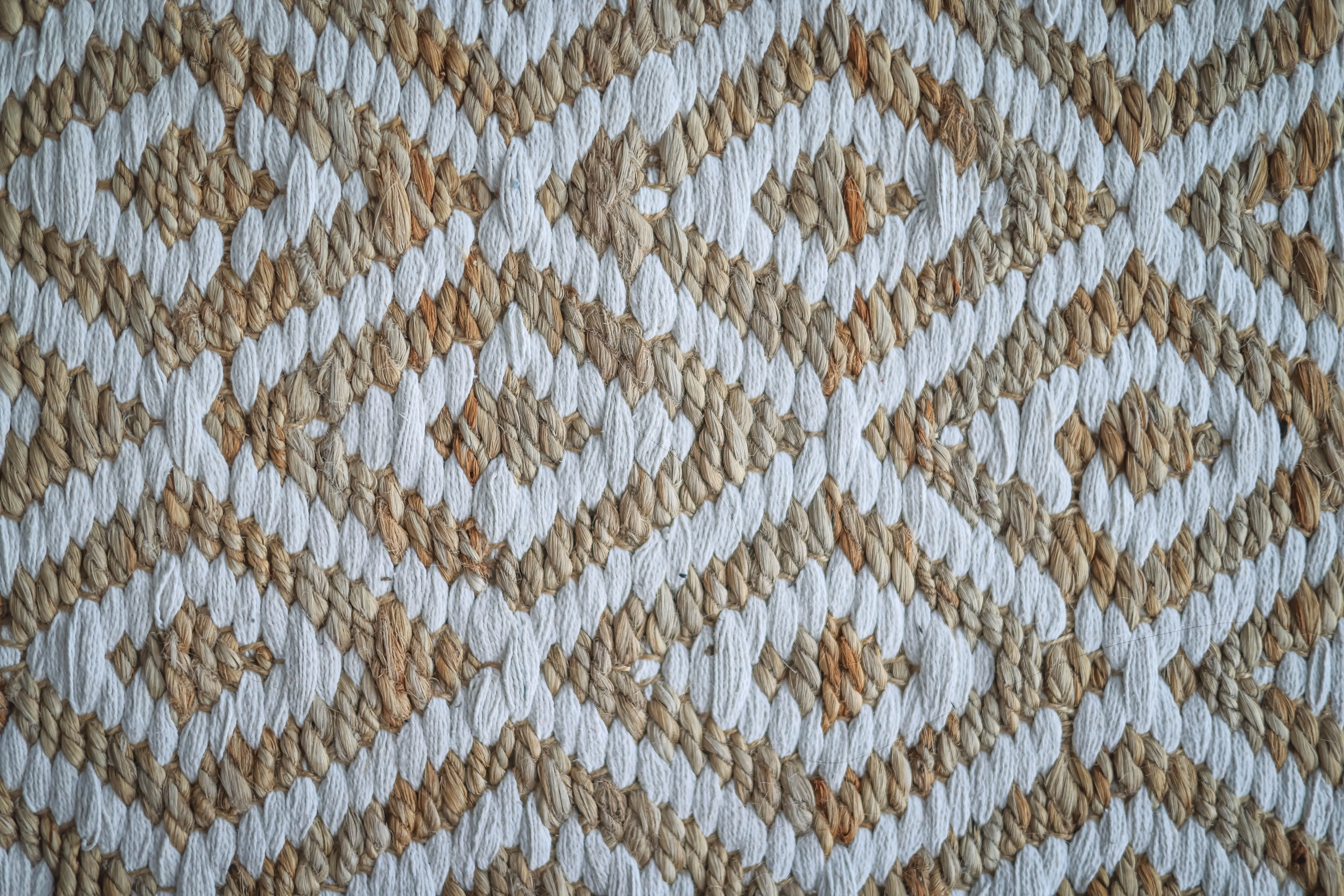 outdoor runner rug Detailed view of a woven rug with a beige and white geometric pattern.