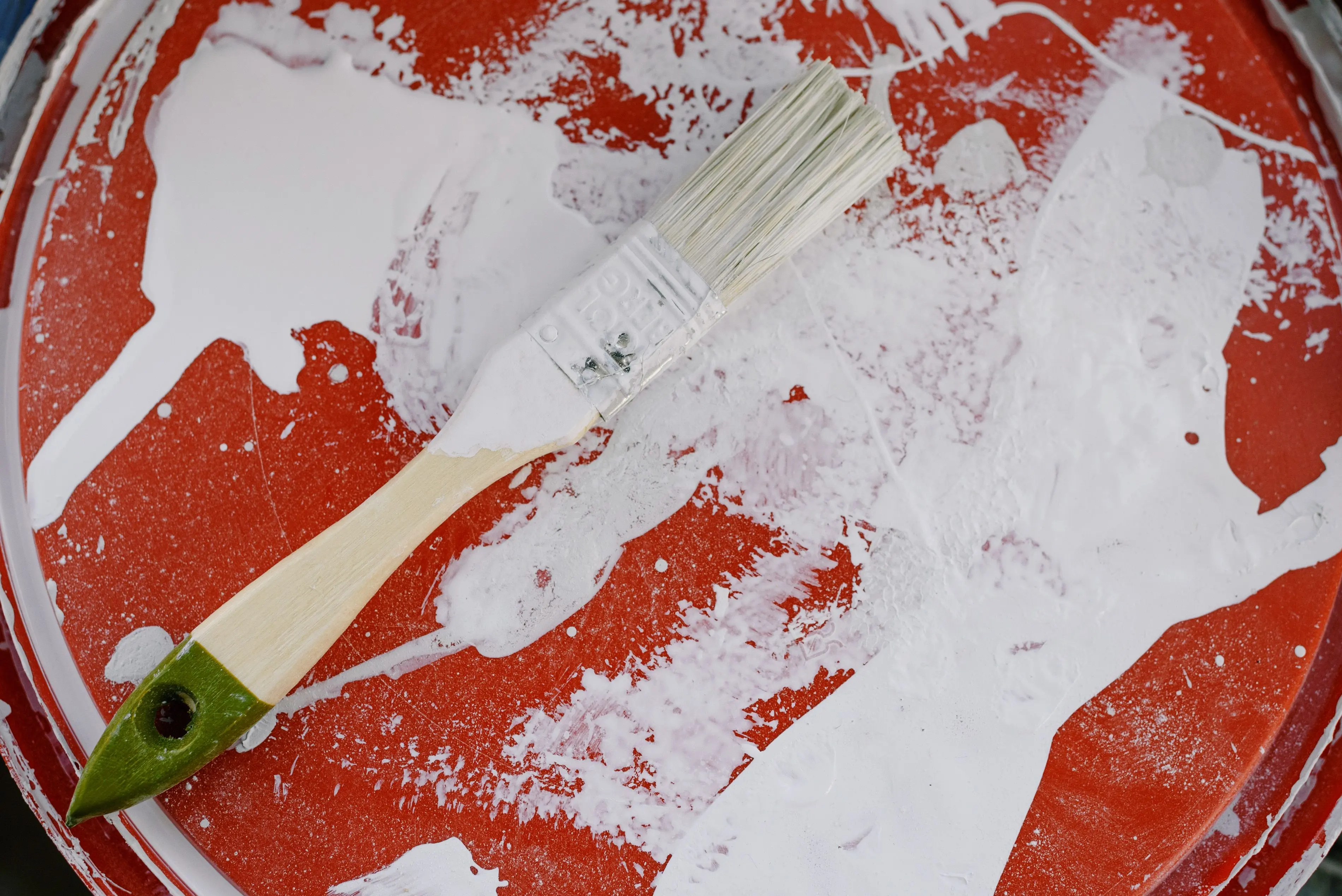 paint chip repair From above of brush with white paint on dirty plastic surface during repair