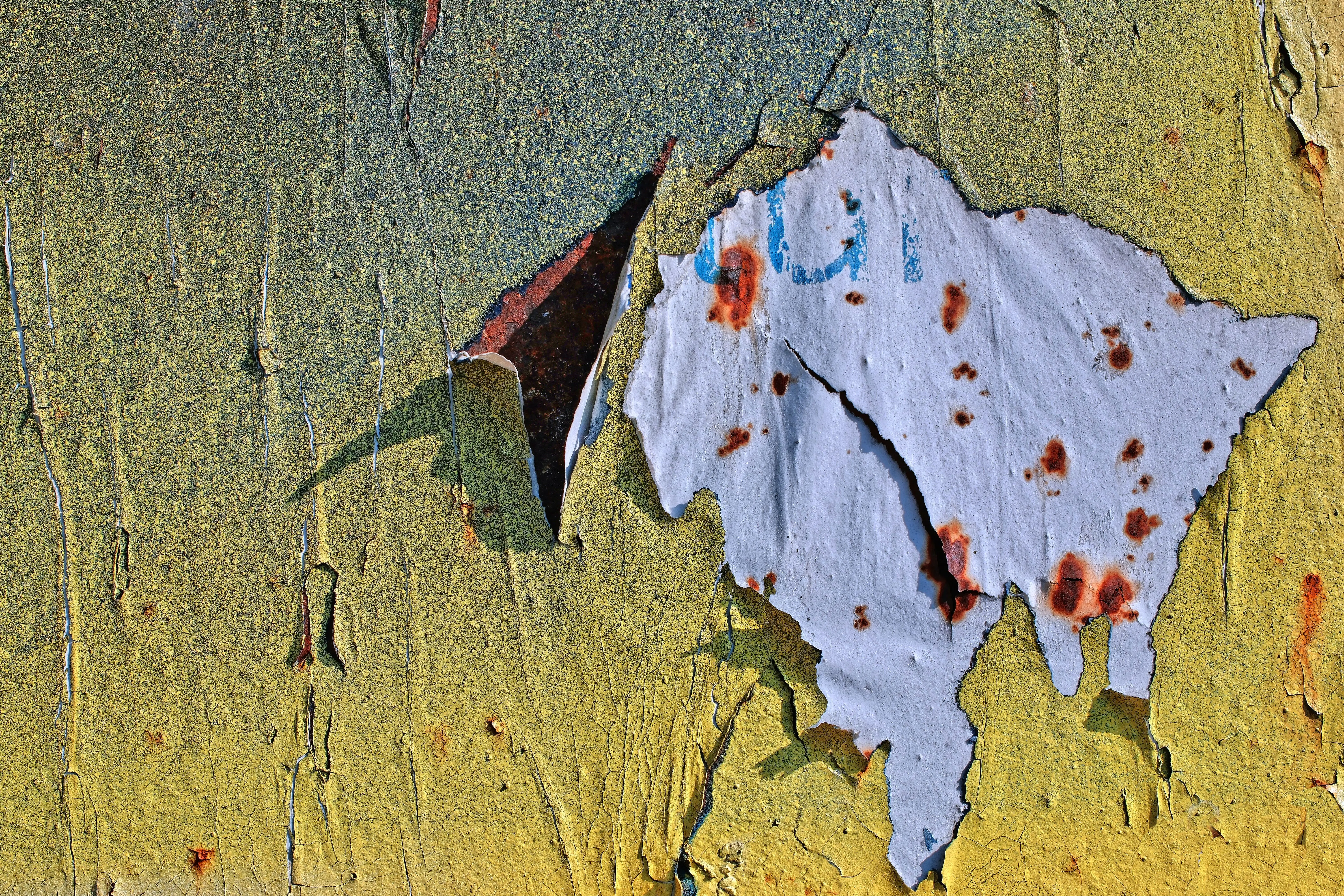 paint chip repair Close-up of peeling paint on a weathered wall showcasing texture and color contrast.