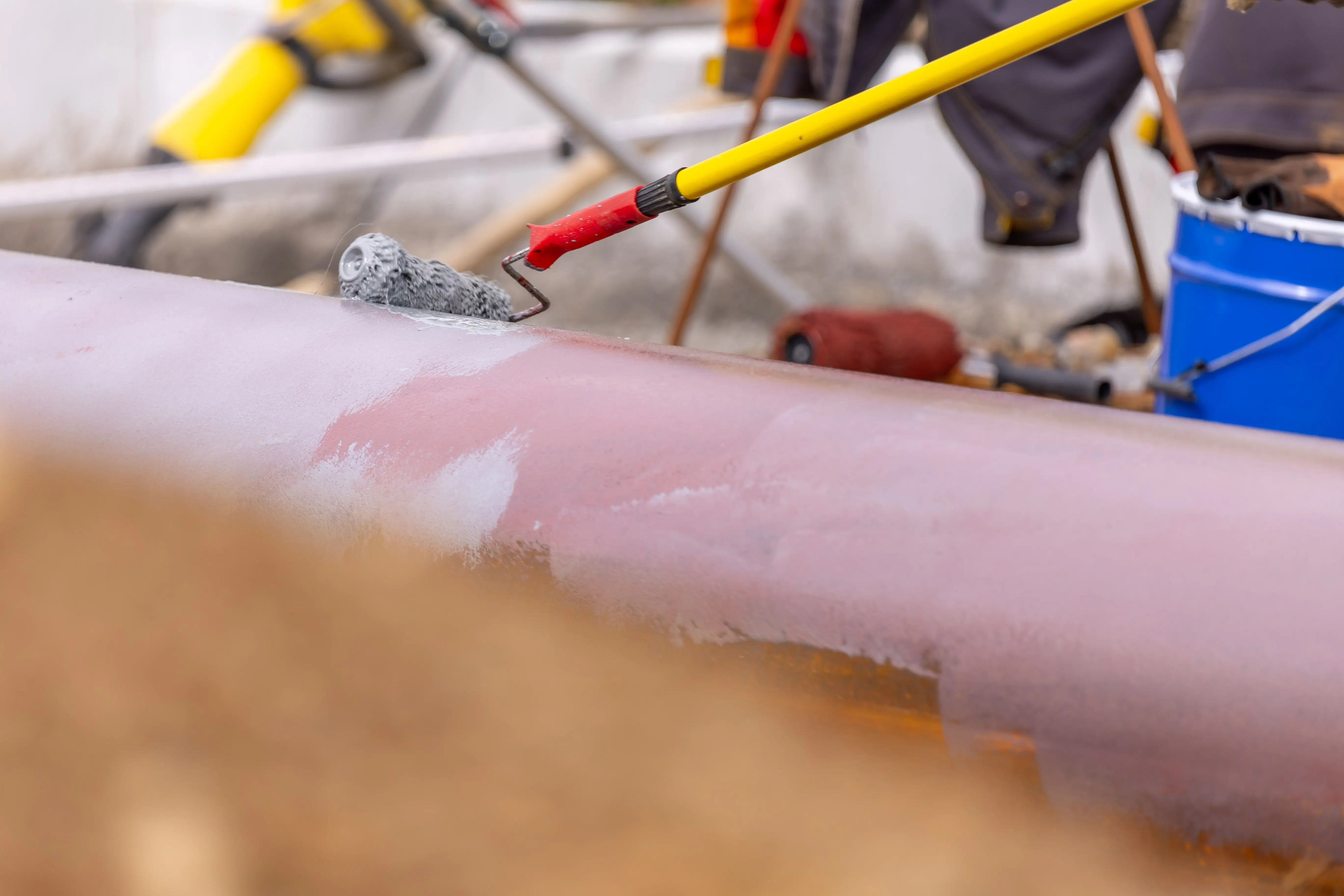 paint for cement floor Close-up of a roller brush painting an industrial pipeline outdoors. Equipment visible in the background.