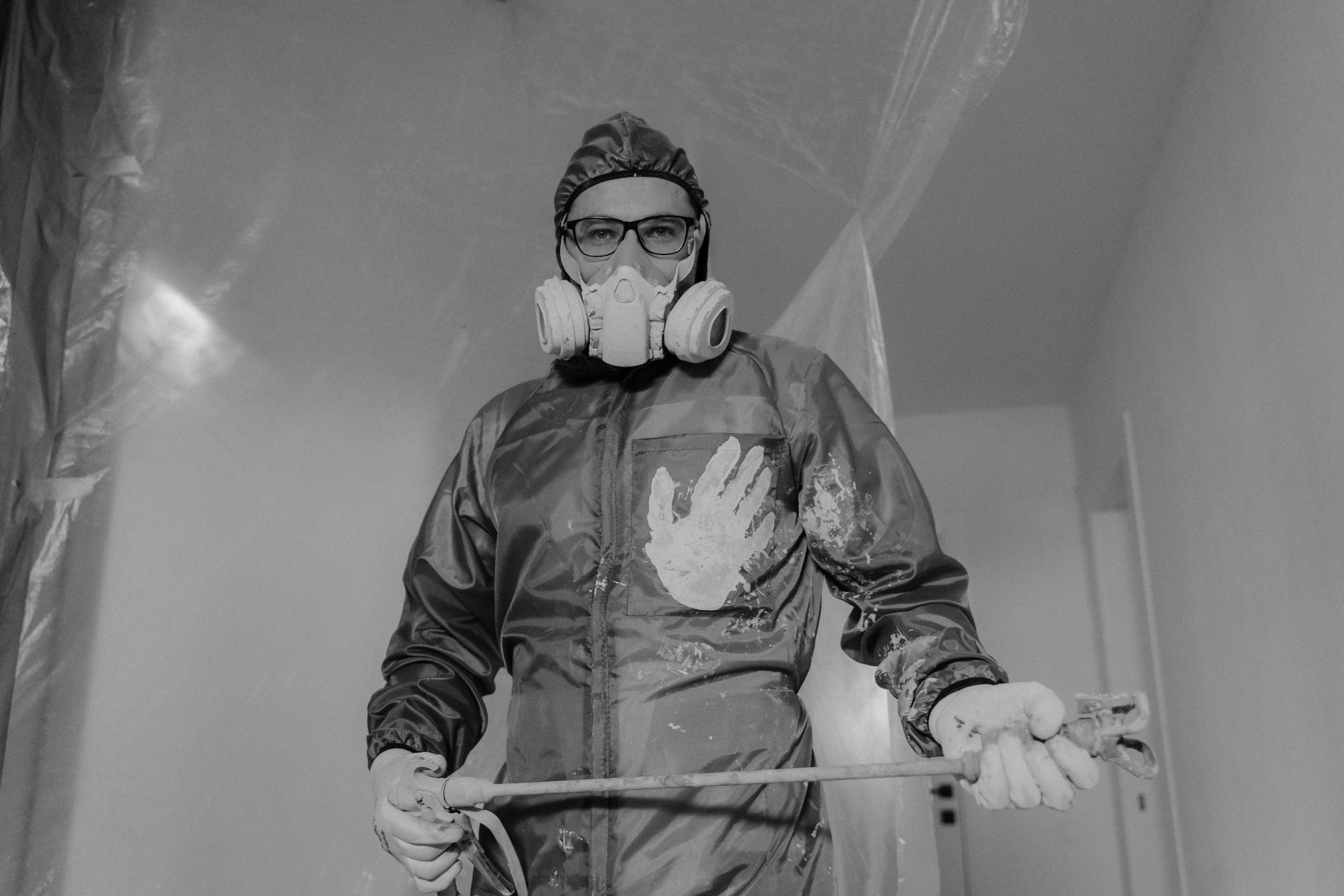 painting cost per square foot A worker in protective gear painting indoors during a home renovation project.