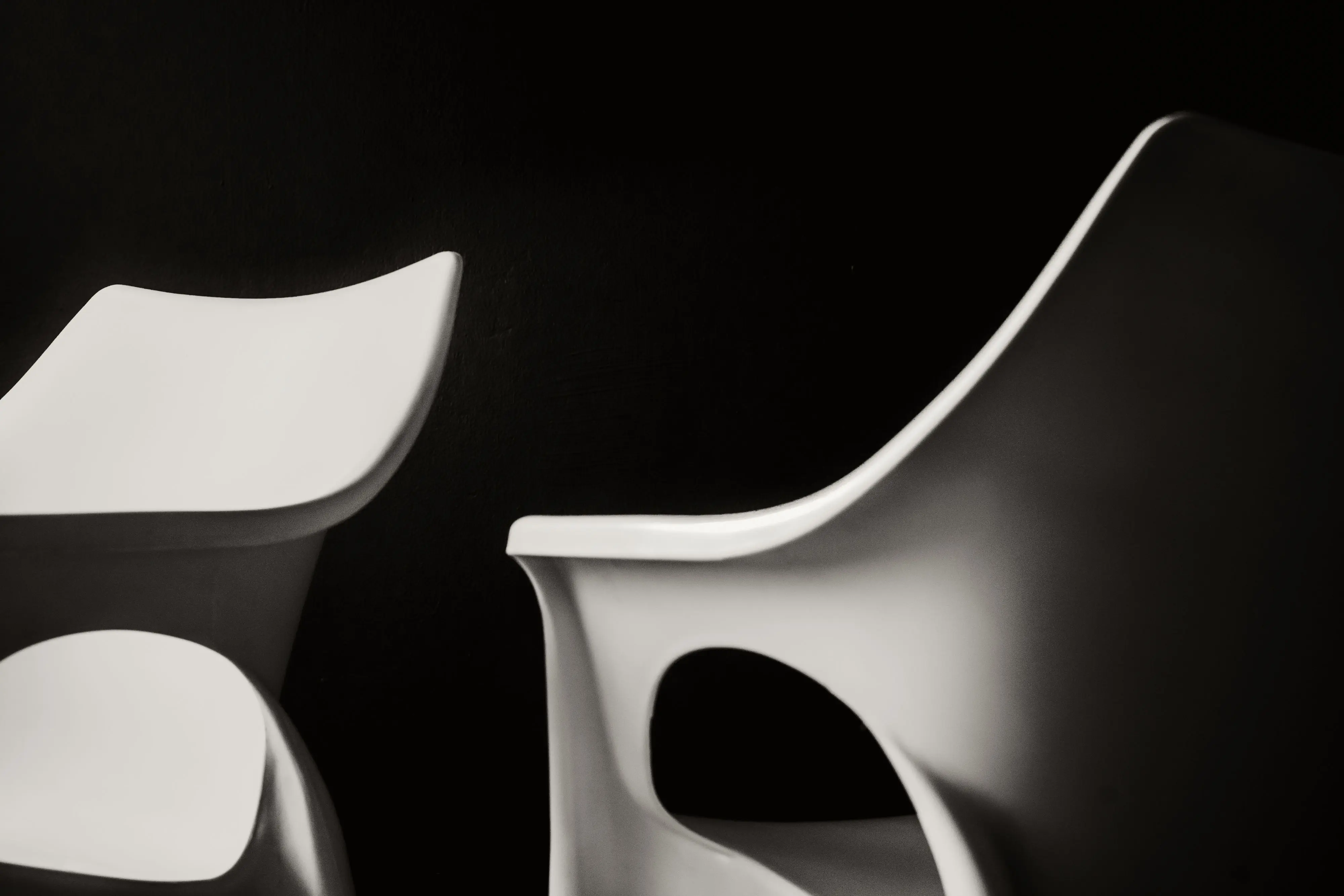 living room chairs set of 2 Artistic black and white photo of modern white plastic chairs with a minimalist design.
