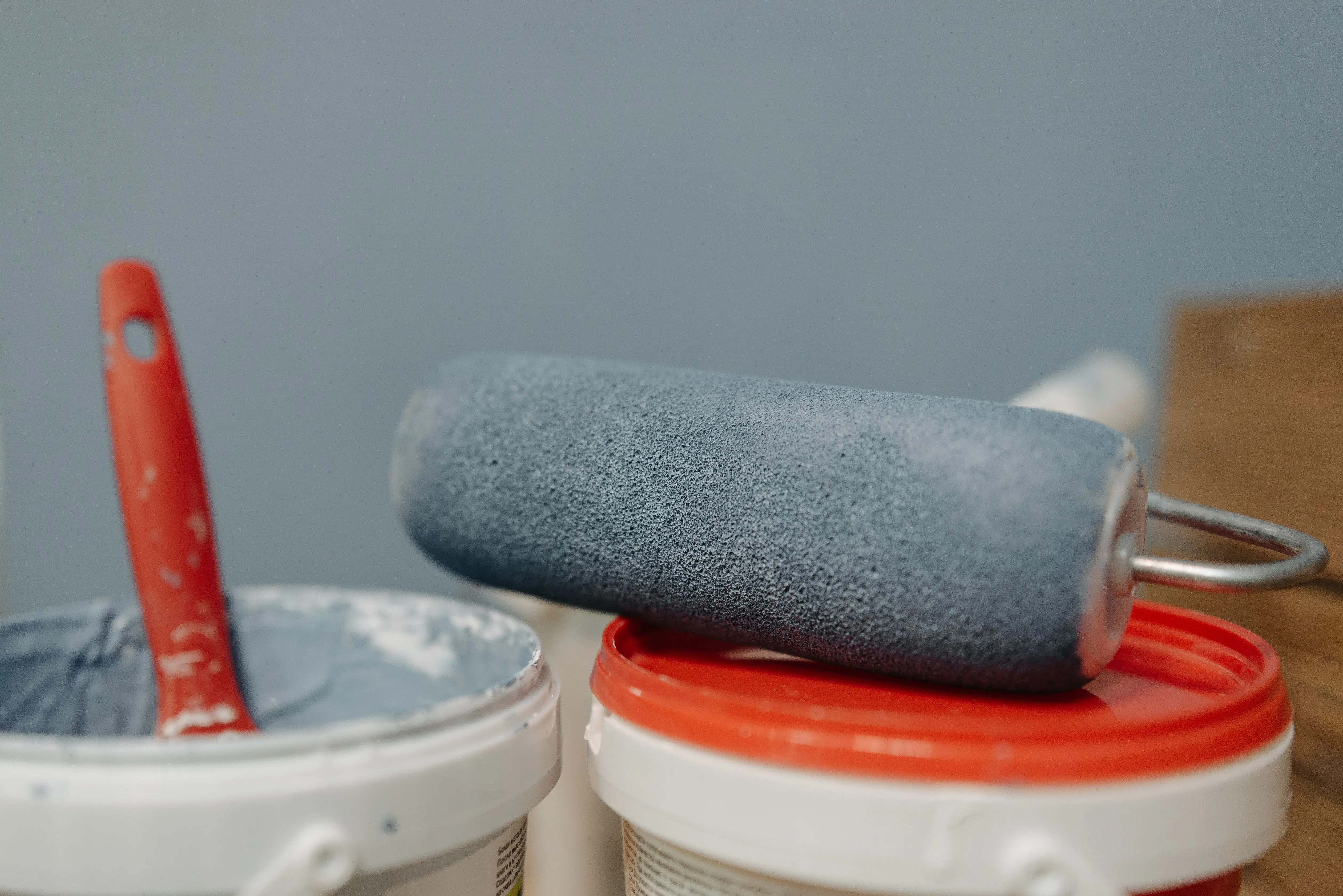paint chip repair A detailed look at a paint roller resting on paint buckets with a blue color scheme.