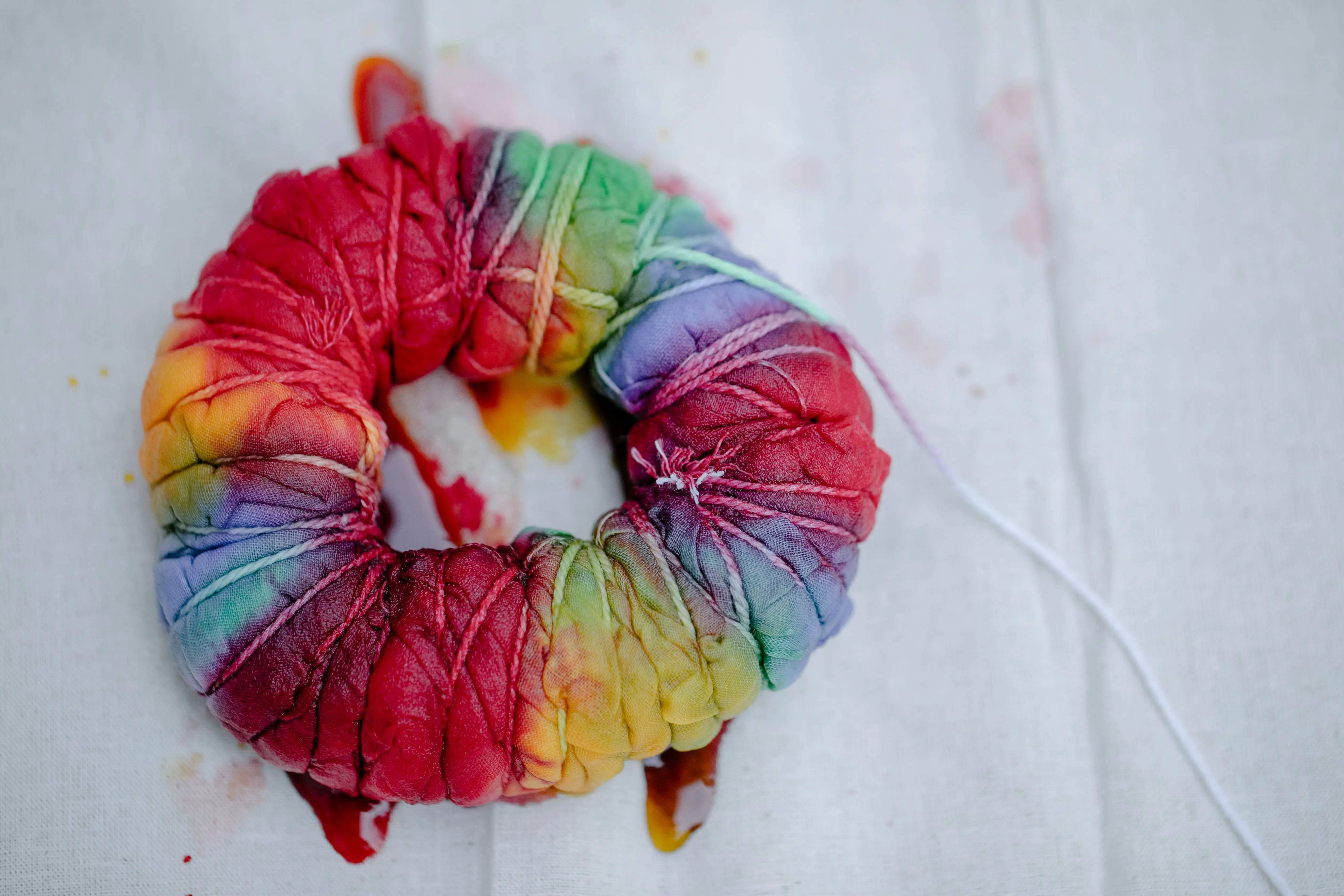 tie dye techniques Top view of pleated textile with multicolored paints tied with threads representing Japanese tie dye technique
