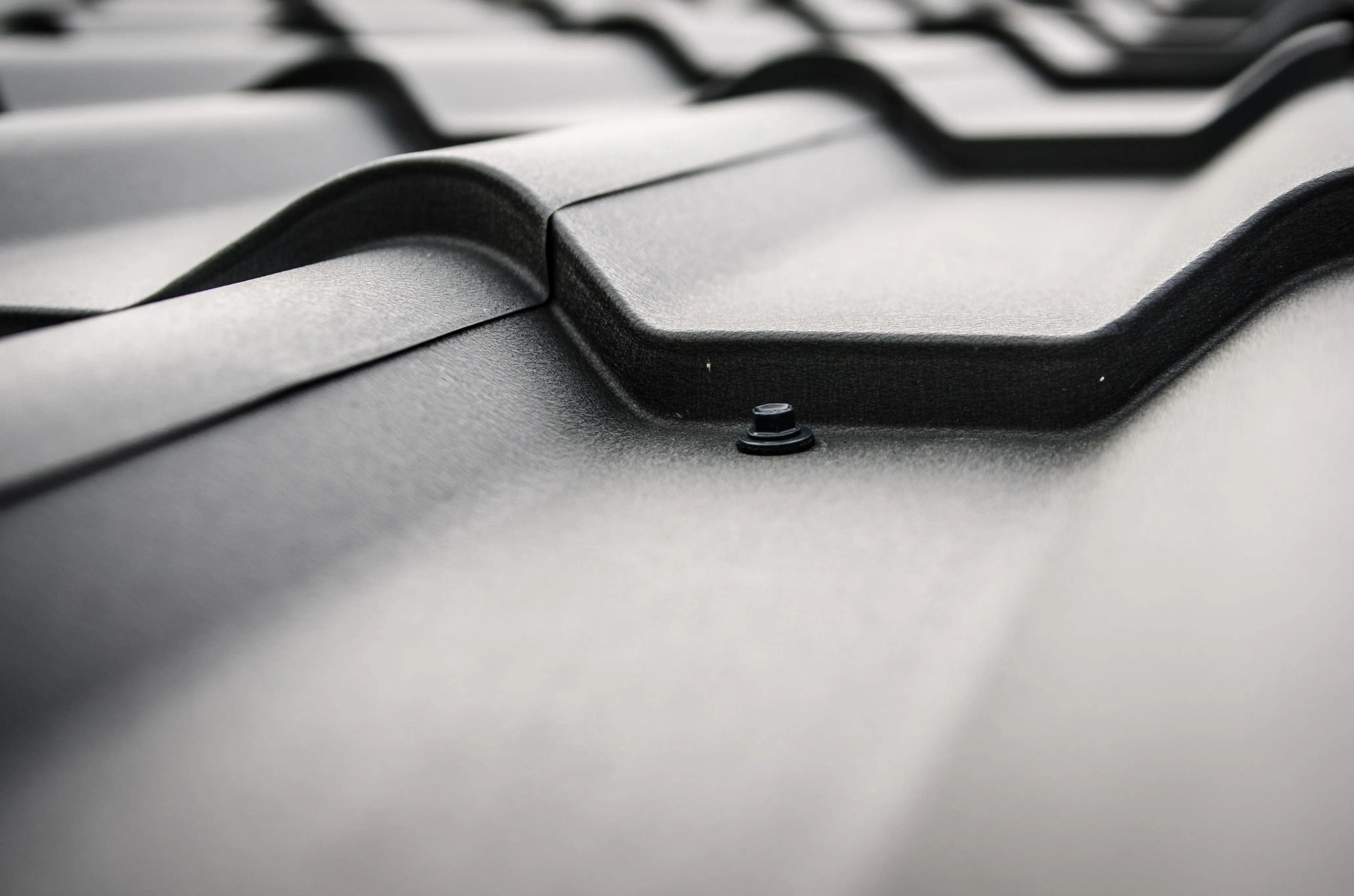steel roof coating Detailed close-up of a black steel roof with prominent rivets and tiles.