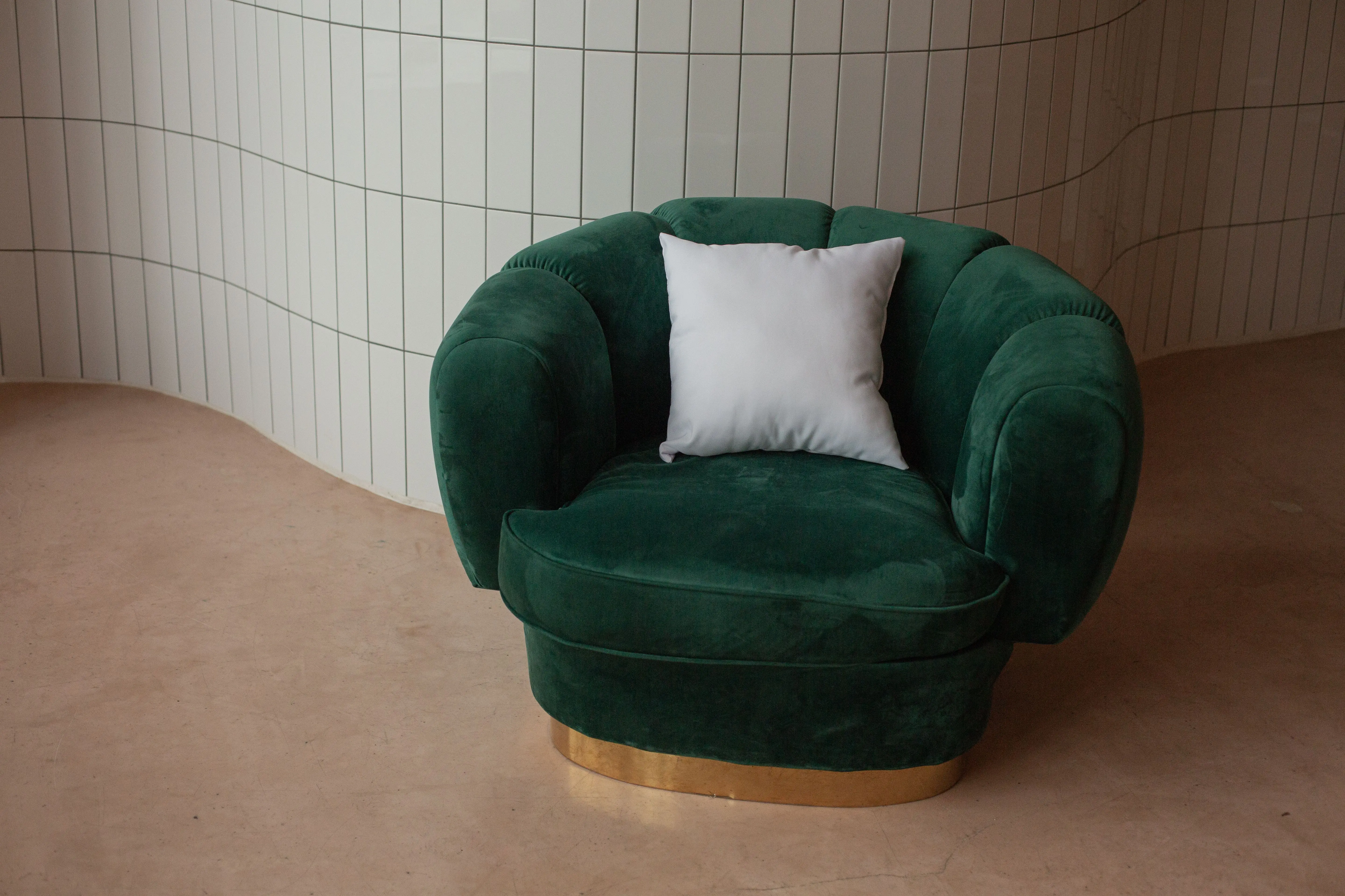 yellow throw pillows Luxurious green velvet armchair with a white pillow set against a stylish tiled backdrop for modern interiors.
