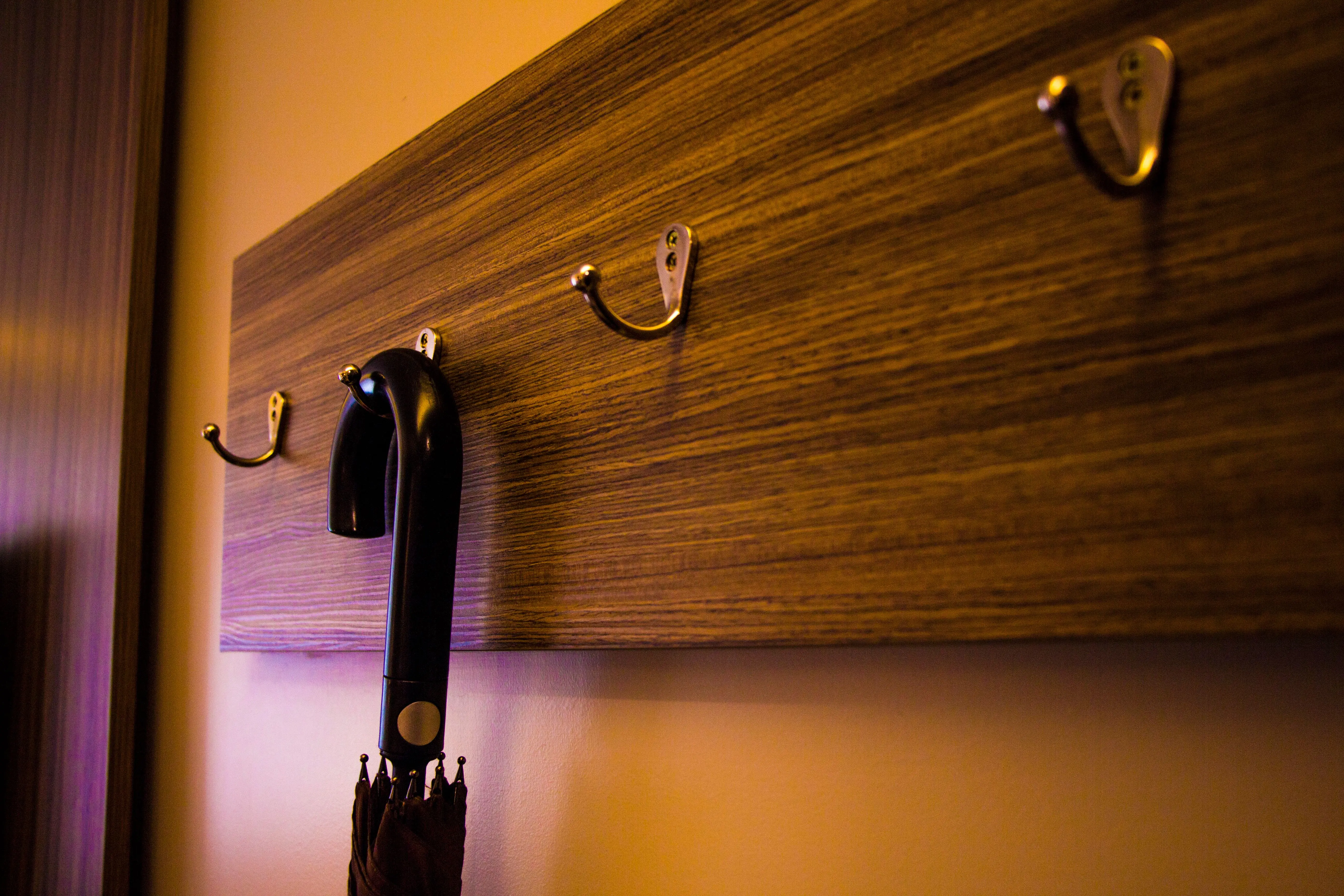 bathroom wall accessories A close-up of a wooden hook board indoors with an umbrella hanging, showcasing a modern design.