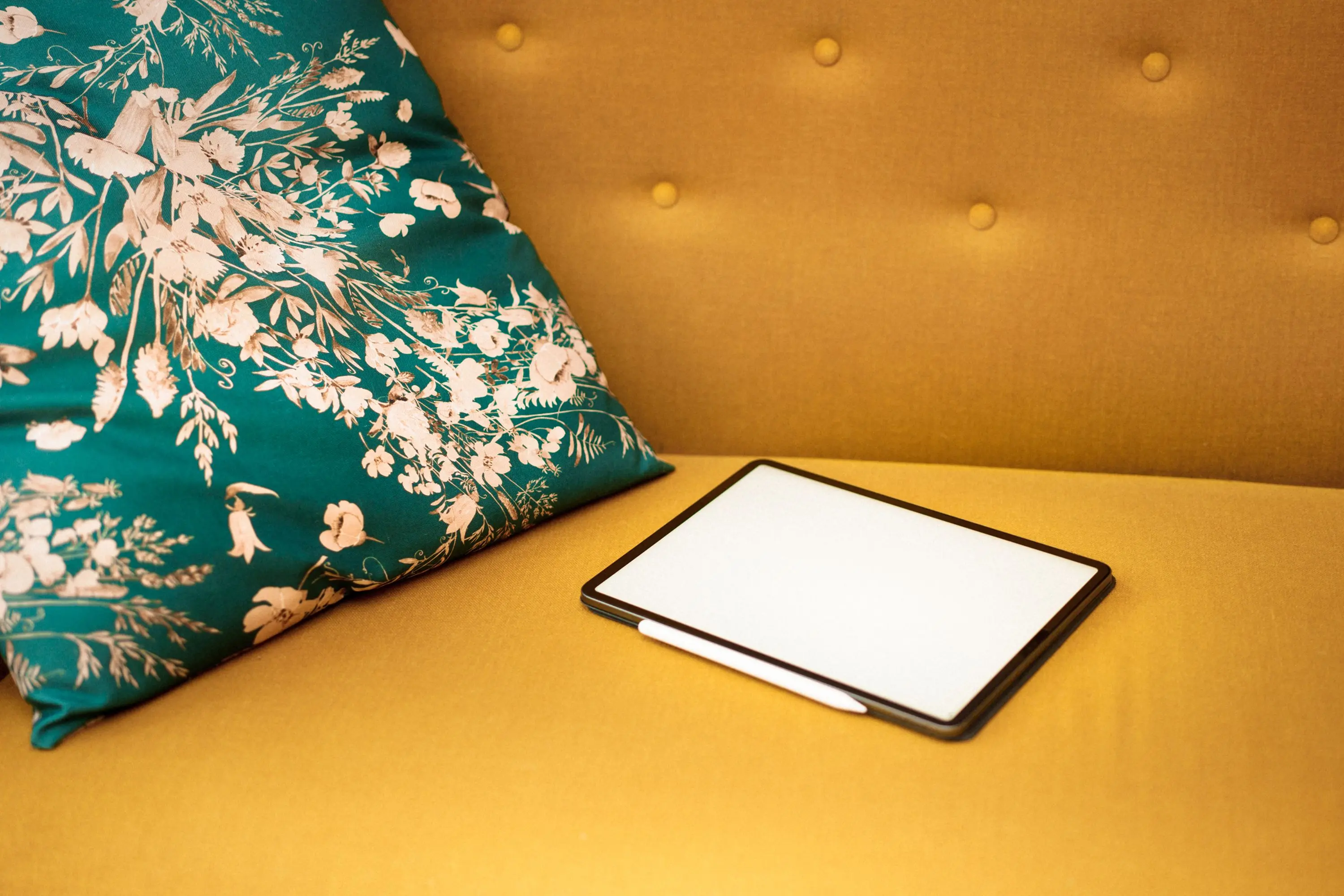 yellow throw pillows Stylish tablet on a mustard sofa with a floral cushion, ideal for tech and home decor concepts.