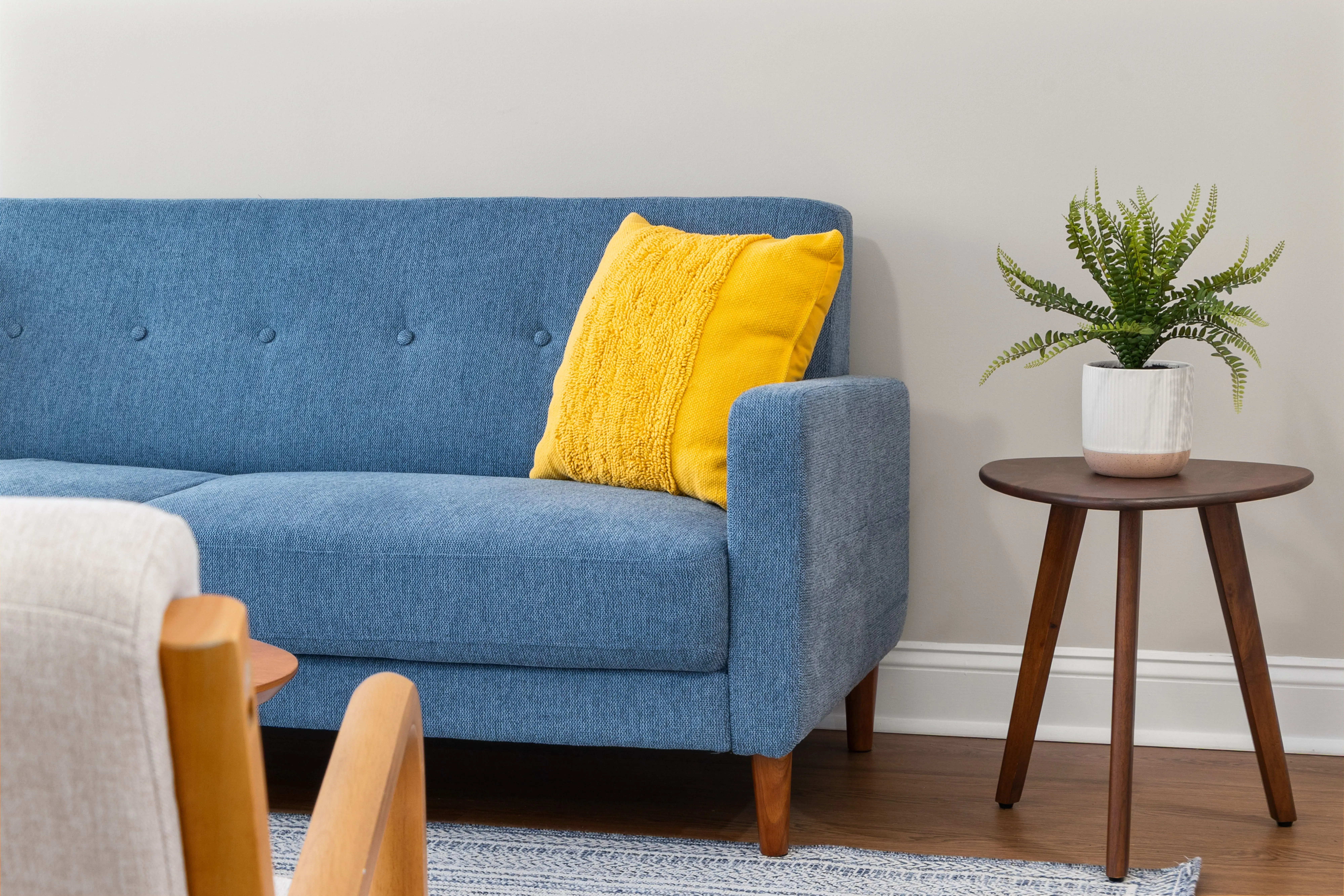 yellow throw pillows Contemporary living room featuring a stylish blue sofa with a bright yellow pillow and a wooden side table.