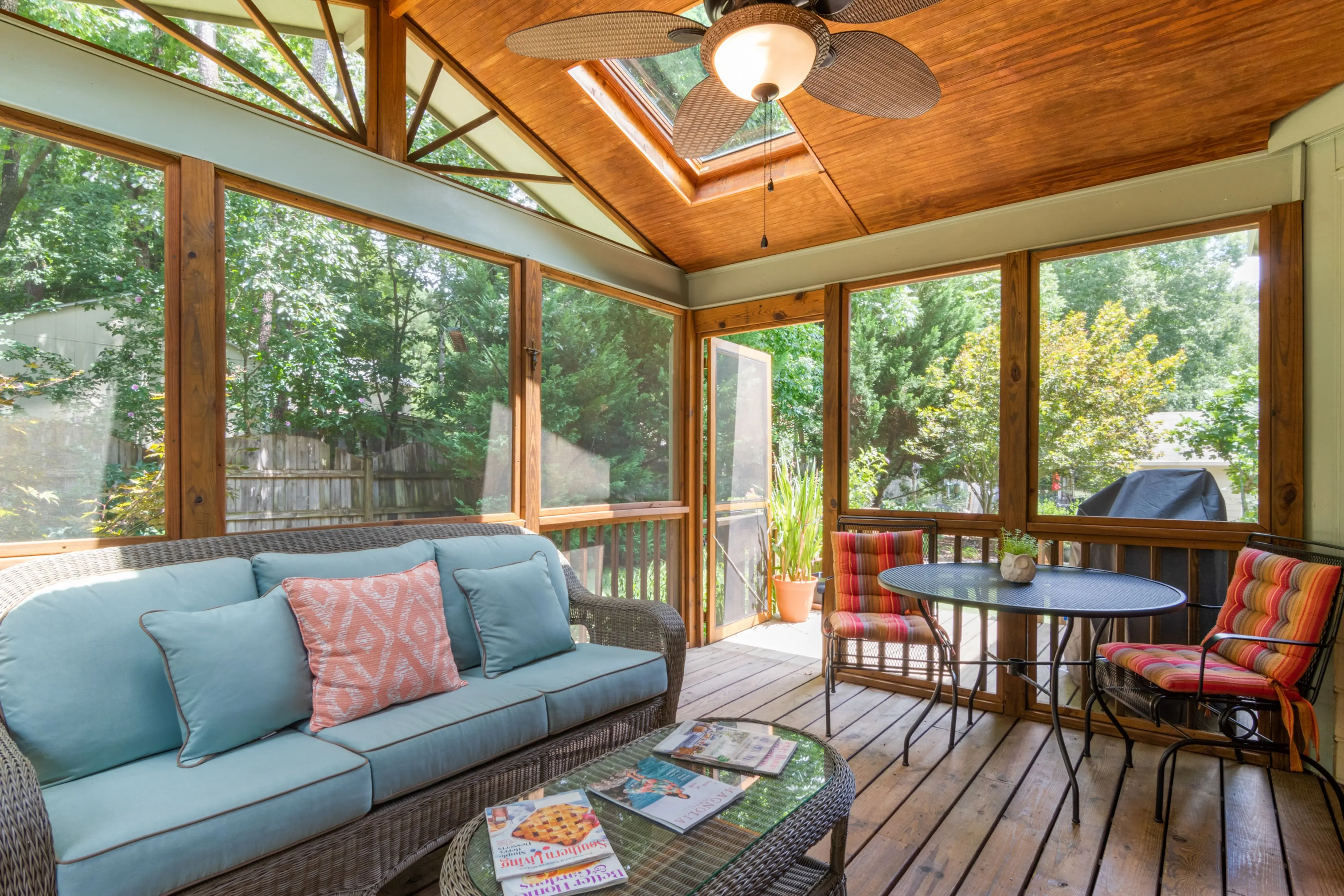 screened in deck Inviting indoor porch with skylight, wicker sofa, and vibrant decor, perfect for relaxation.