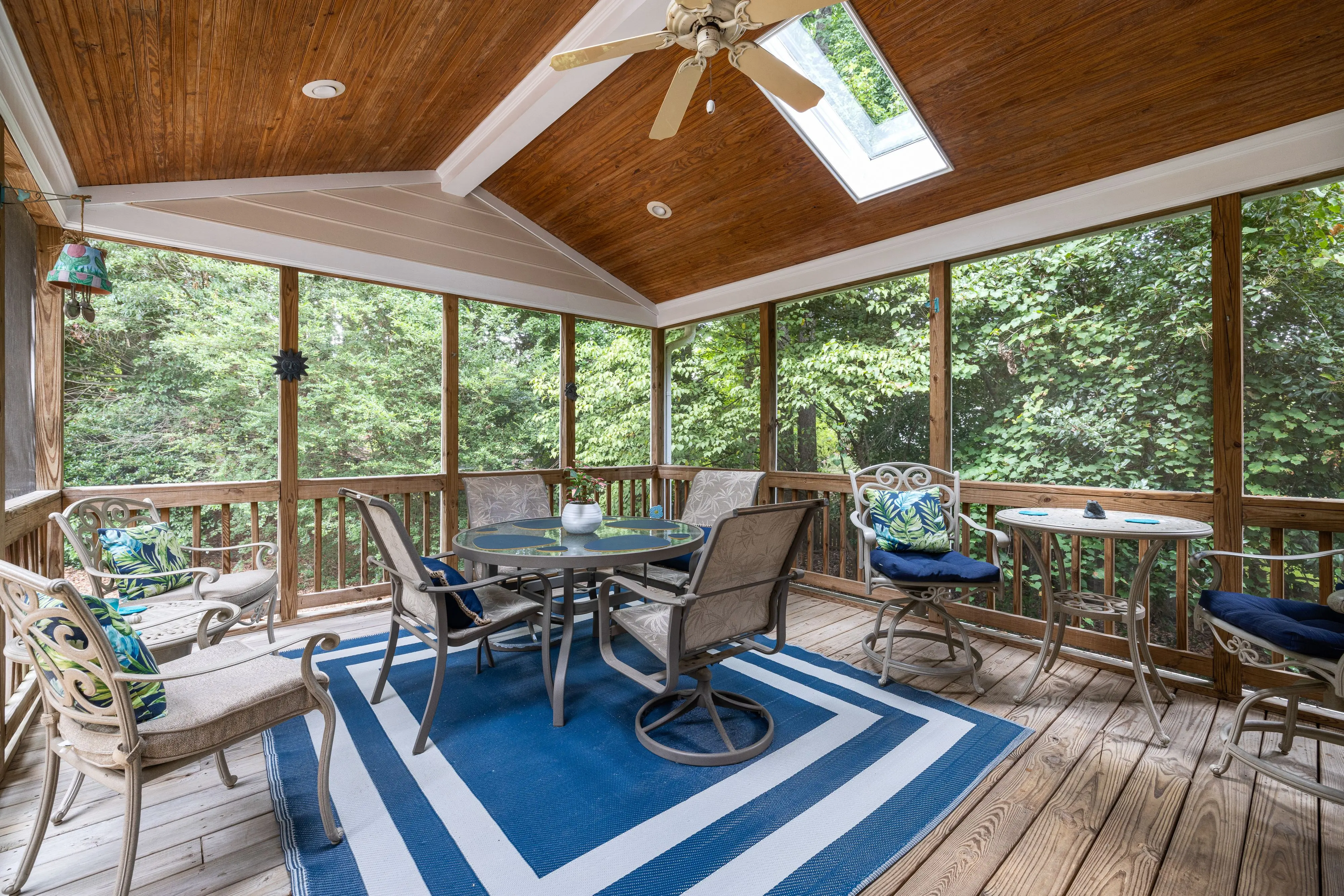 screened in deck Spacious indoor terrace with elegant patio furniture and forest view, ideal for relaxation.