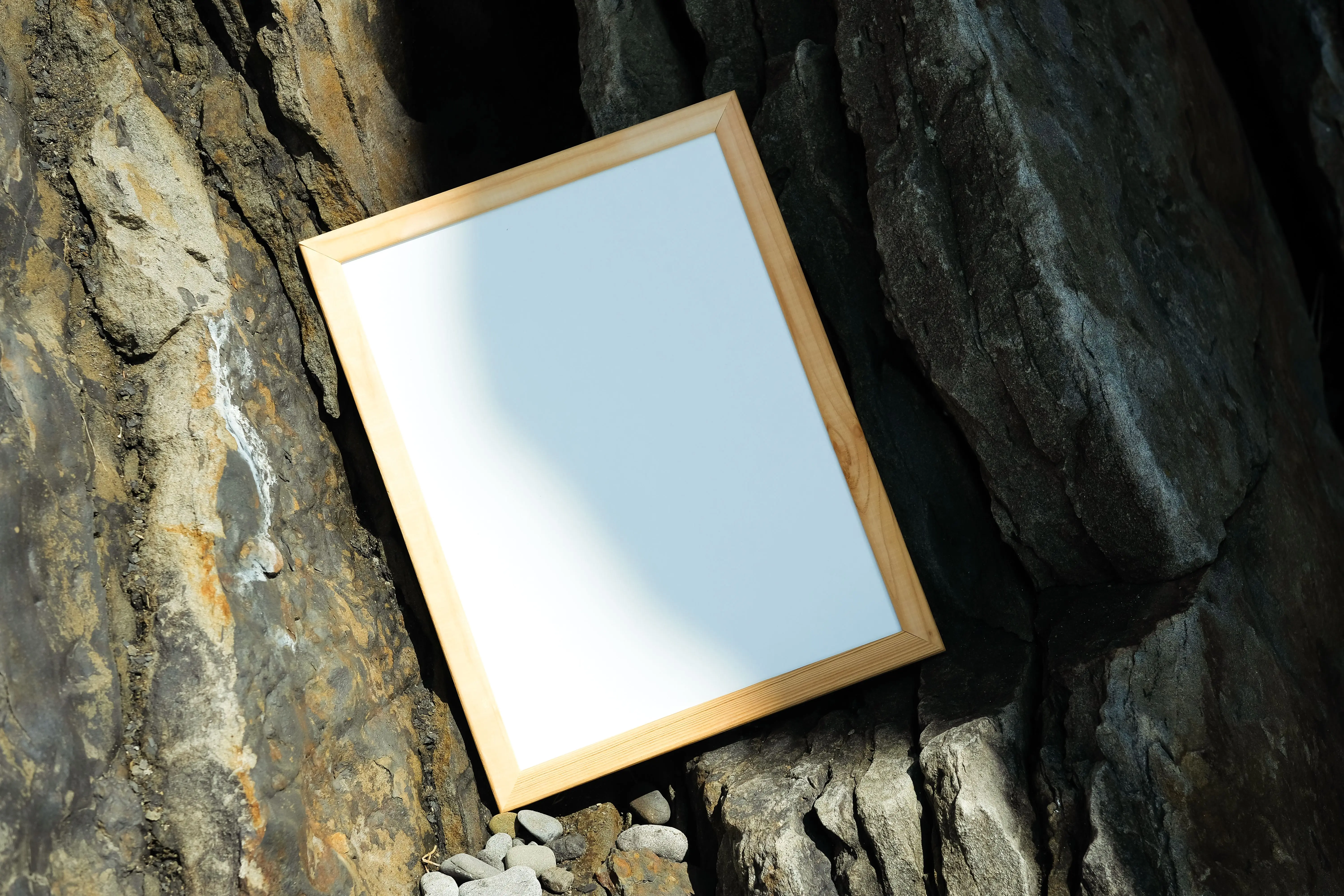 beach wall art Blank wooden frame on rocky surface with shadow, ideal for mockup designs.