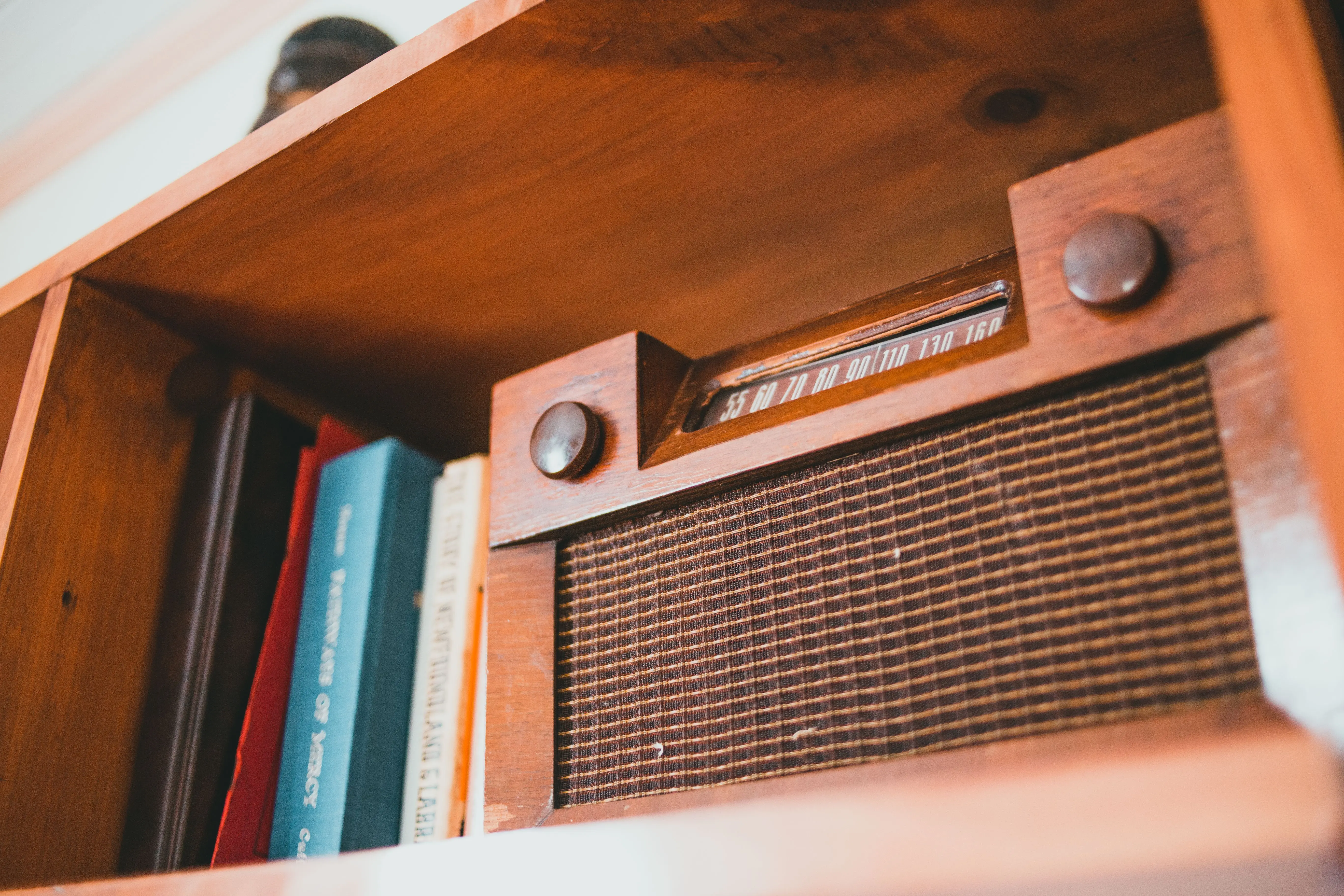 wood wall shelf A close-up of a vintage radio on a wooden bookshelf with books surrounding it.