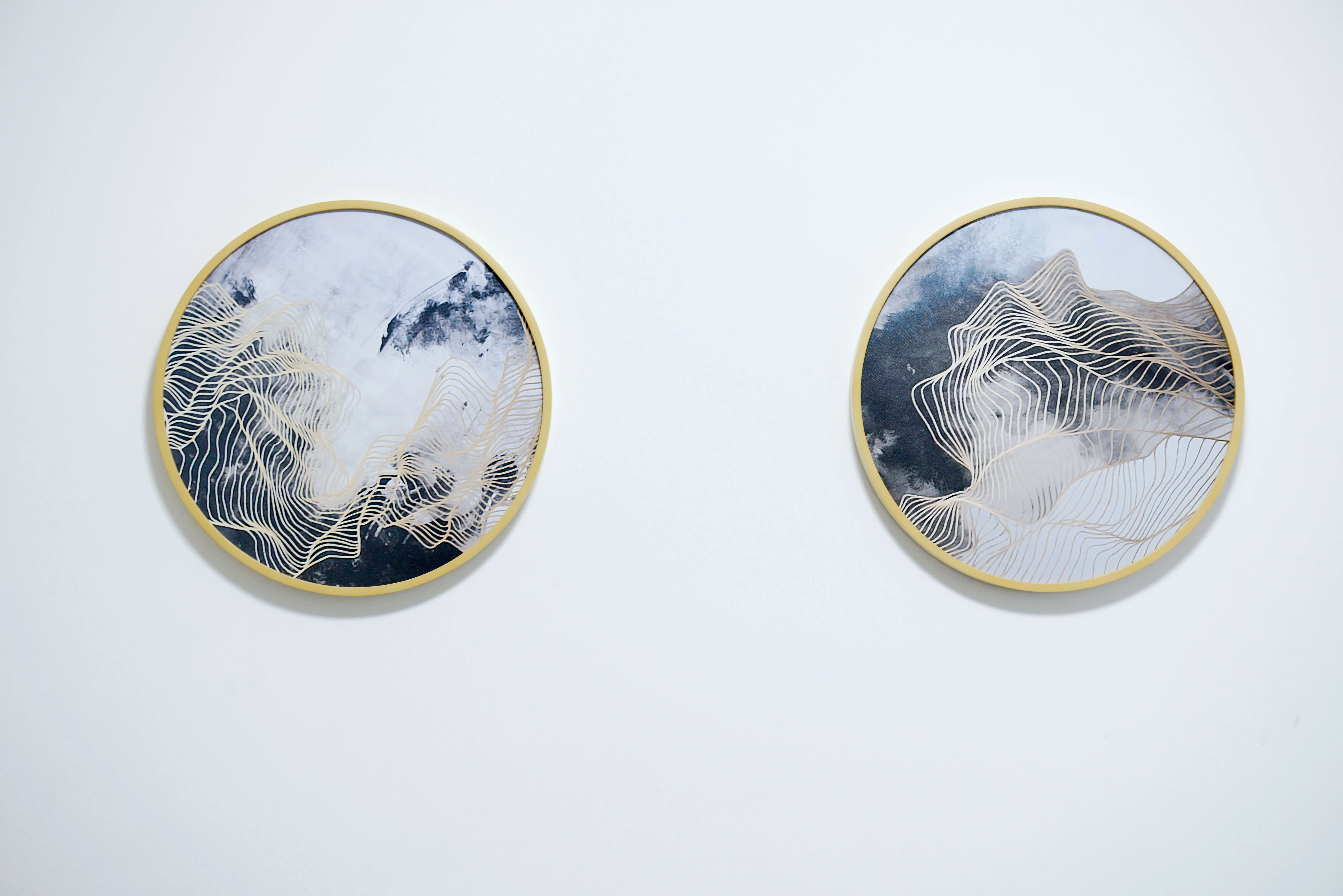 abstract art prints Two abstract circular paintings with gold frames on a white wall, capturing modern minimalist design.