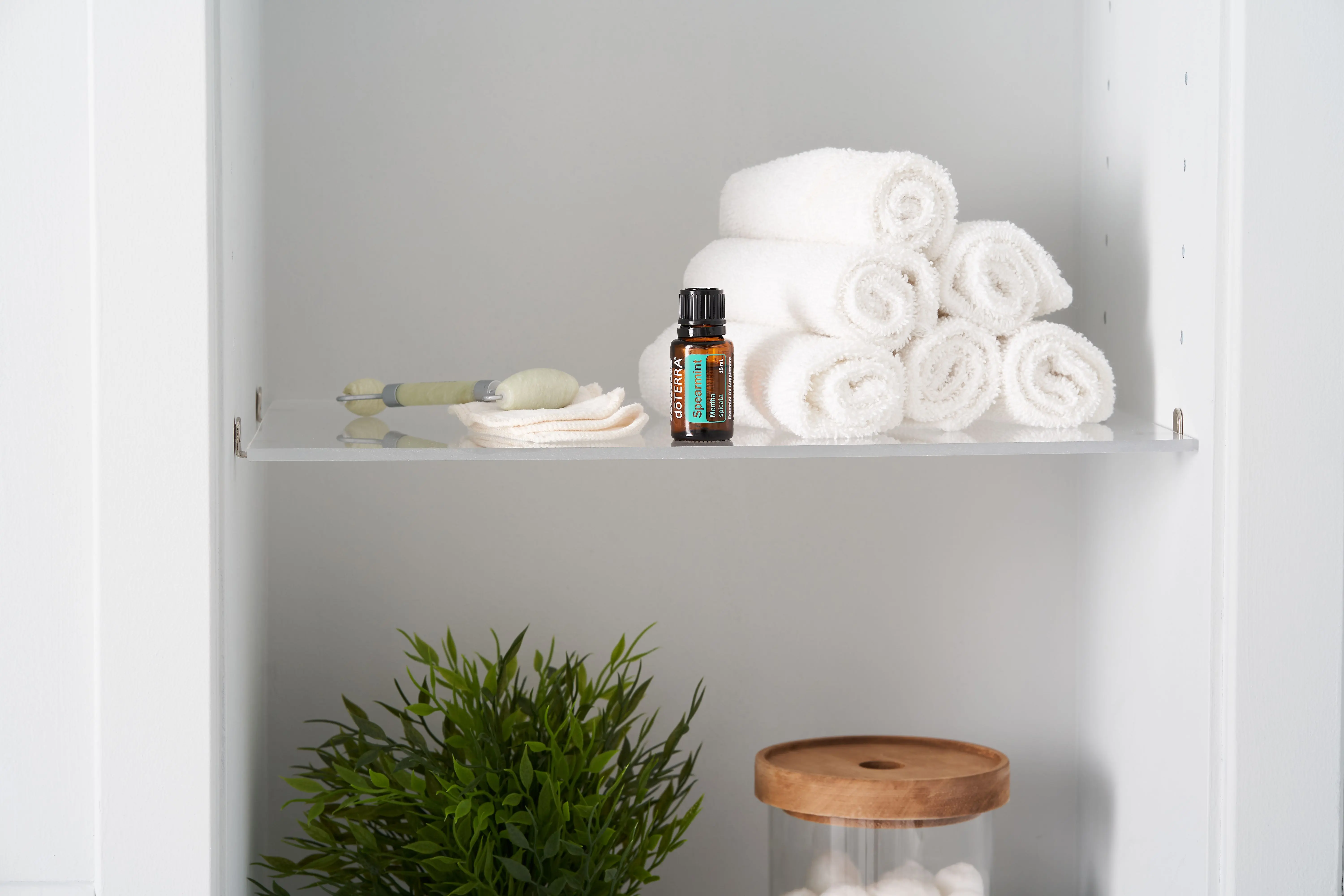 vanity shelves Neatly folded towels with essential oil and jade roller on a shelf for a relaxing spa ambiance.