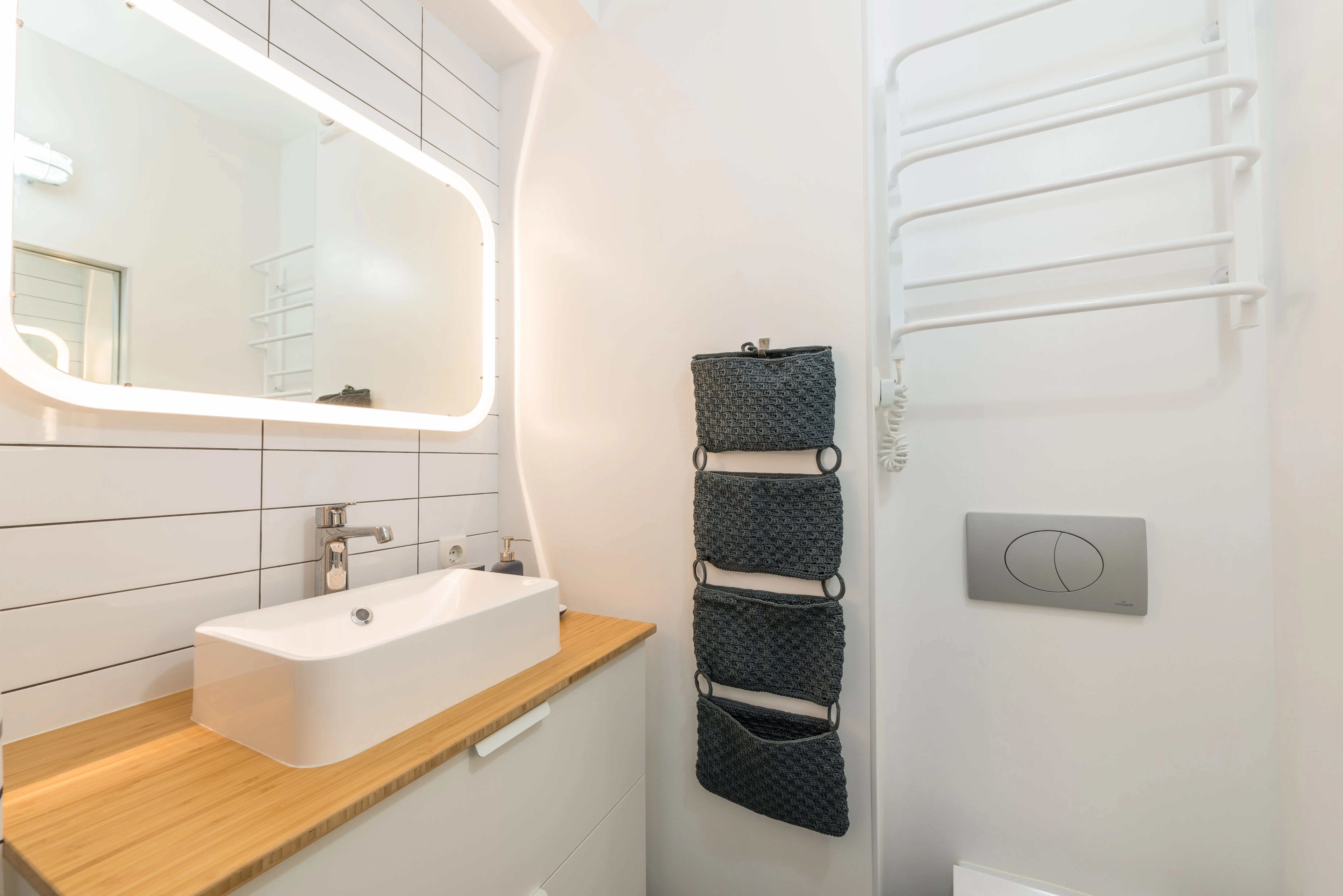 under sink cabinet Interior of small modern bathroom with ceramic sink placed on white cabinet with wooden top under illuminated mirror
