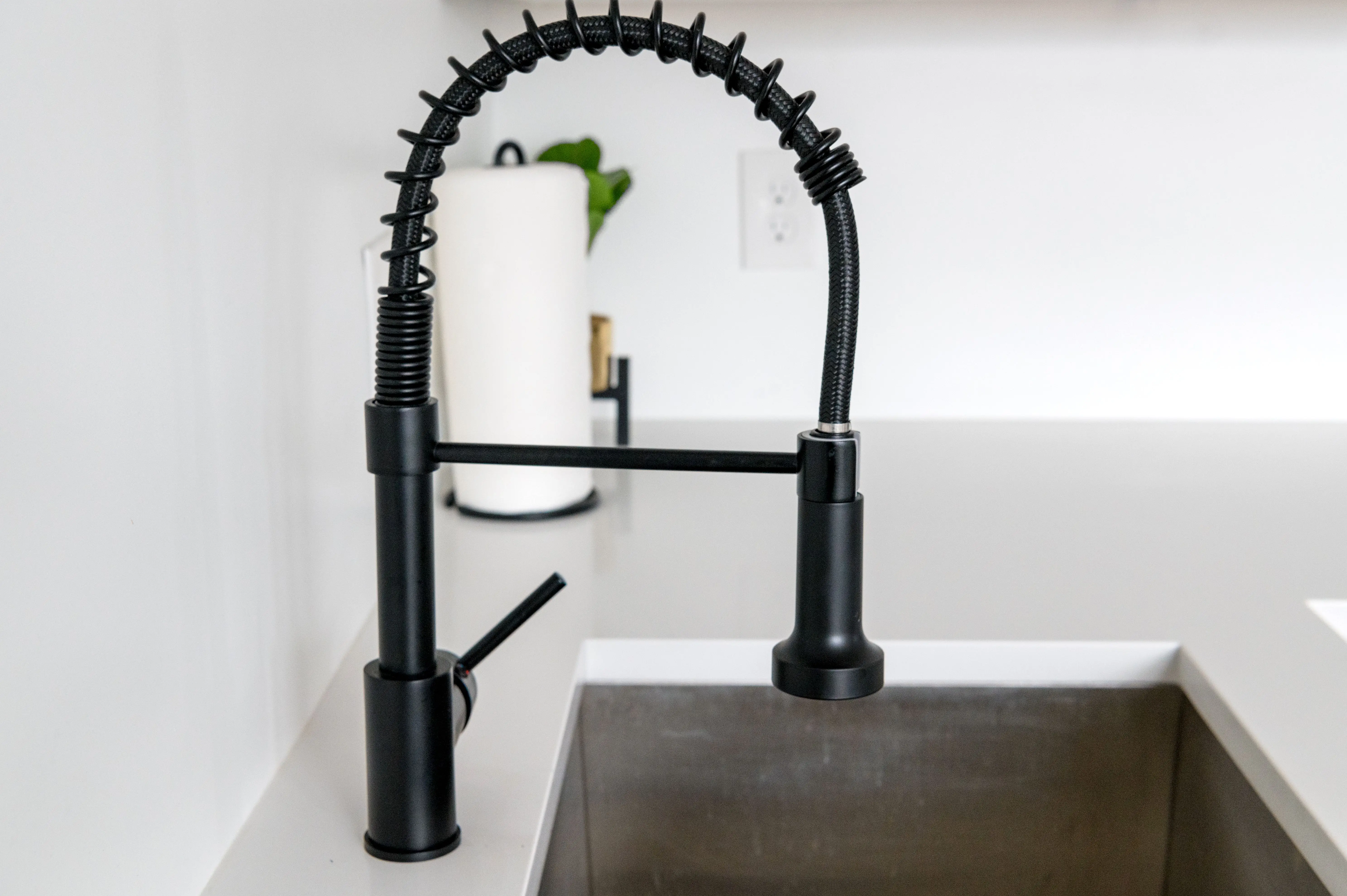 black cabinet hardware Sleek black faucet on white countertop in modern kitchen. Ideal for minimalist and contemporary designs.