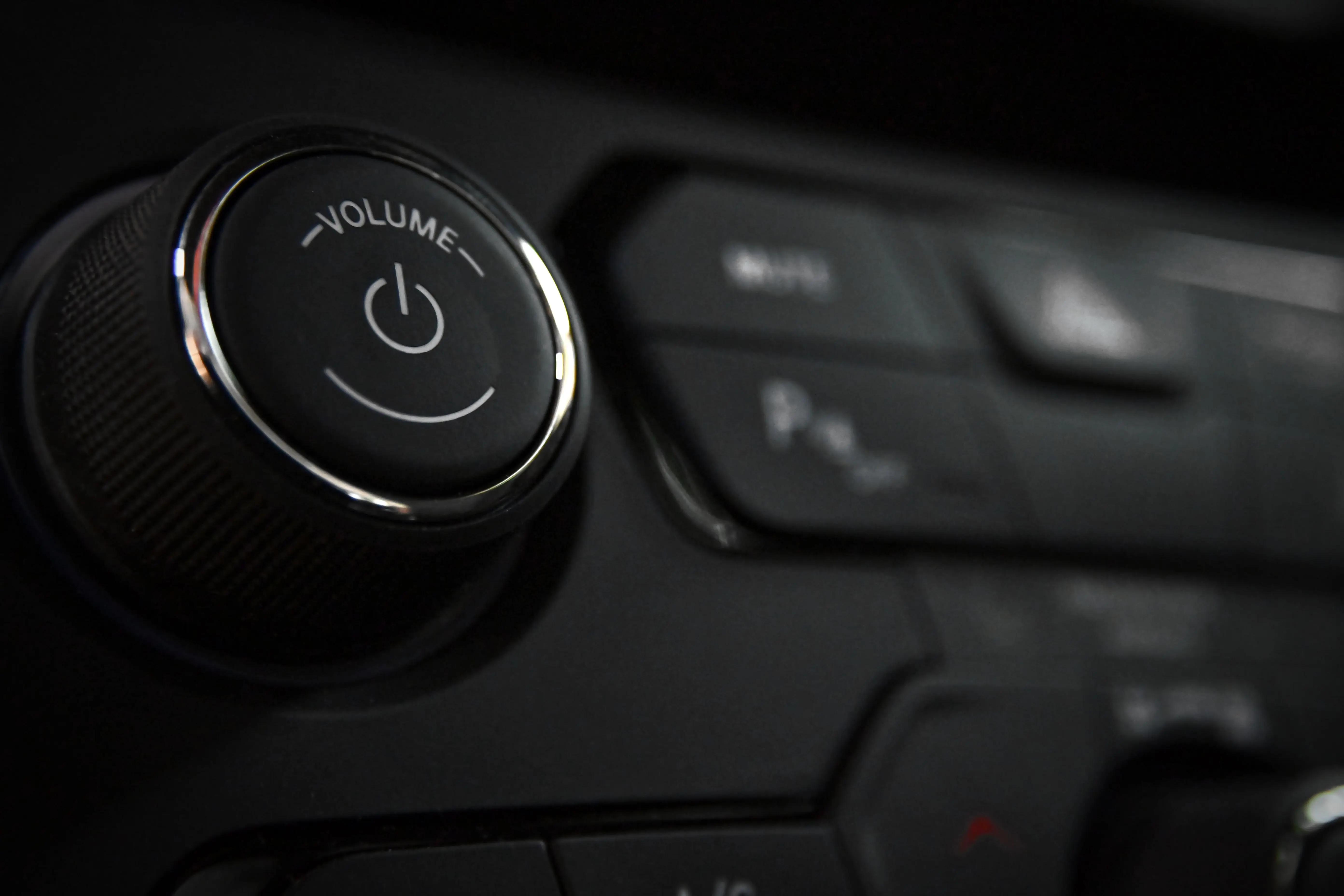 black cabinet knobs Detailed close-up of a vehicle's volume control knob and dashboard buttons indoors.