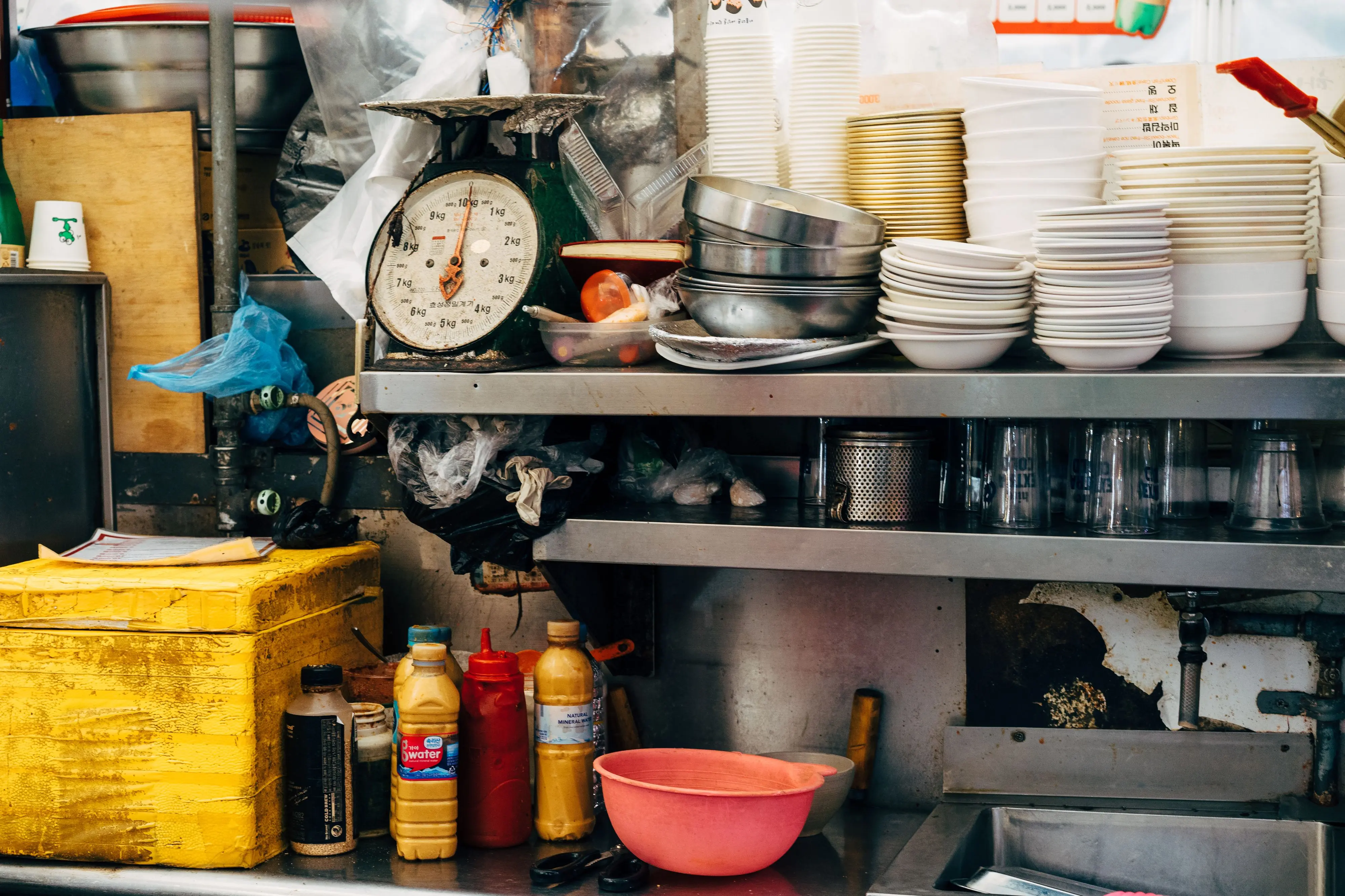 under sink cabinet Vibrant kitchen scene in Seoul with assorted bowls, scales, and condiments creating a bustling atmosphere.