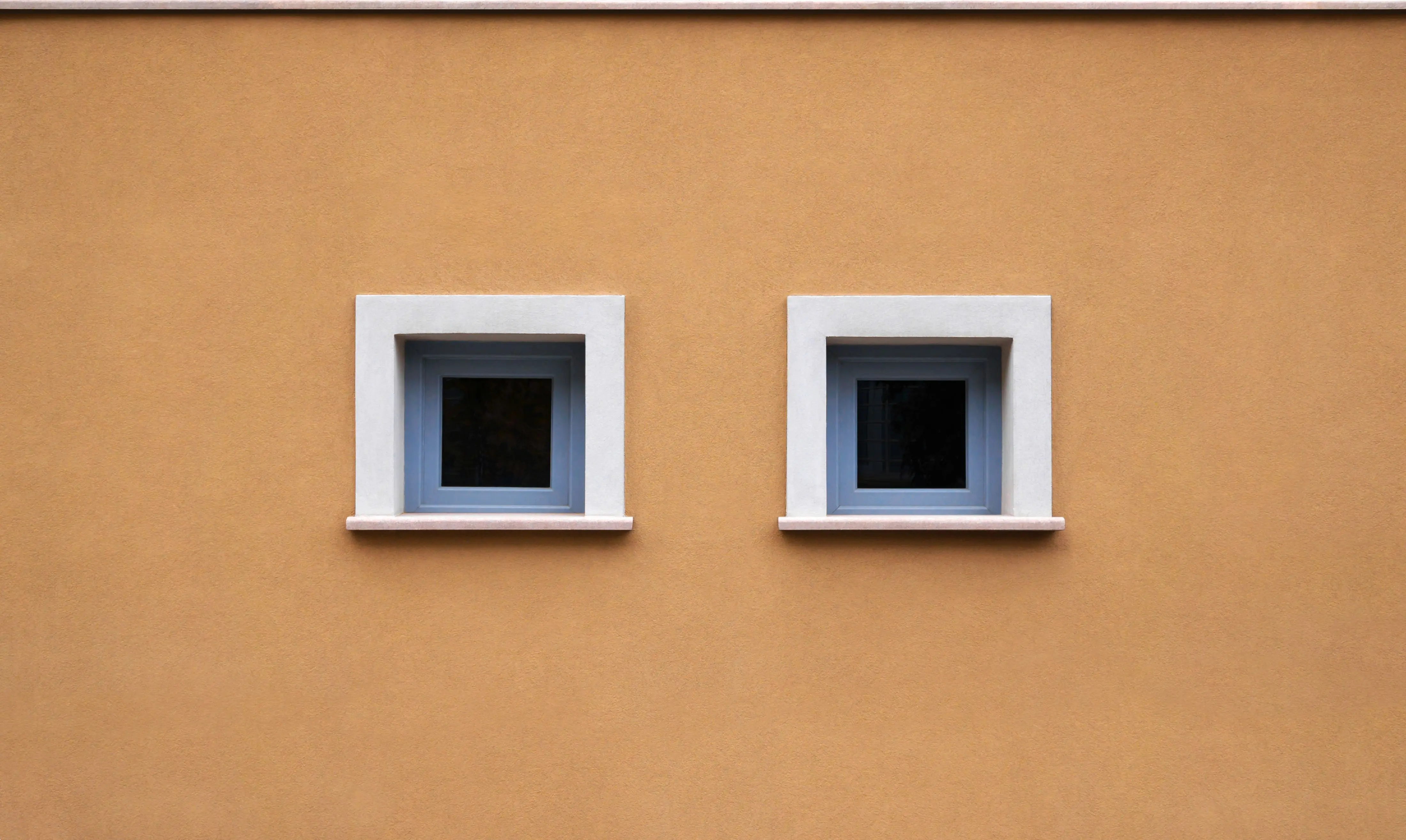 dark grey kitchen cabinets A minimalist architectural shot of an orange wall featuring two square windows framed in white.