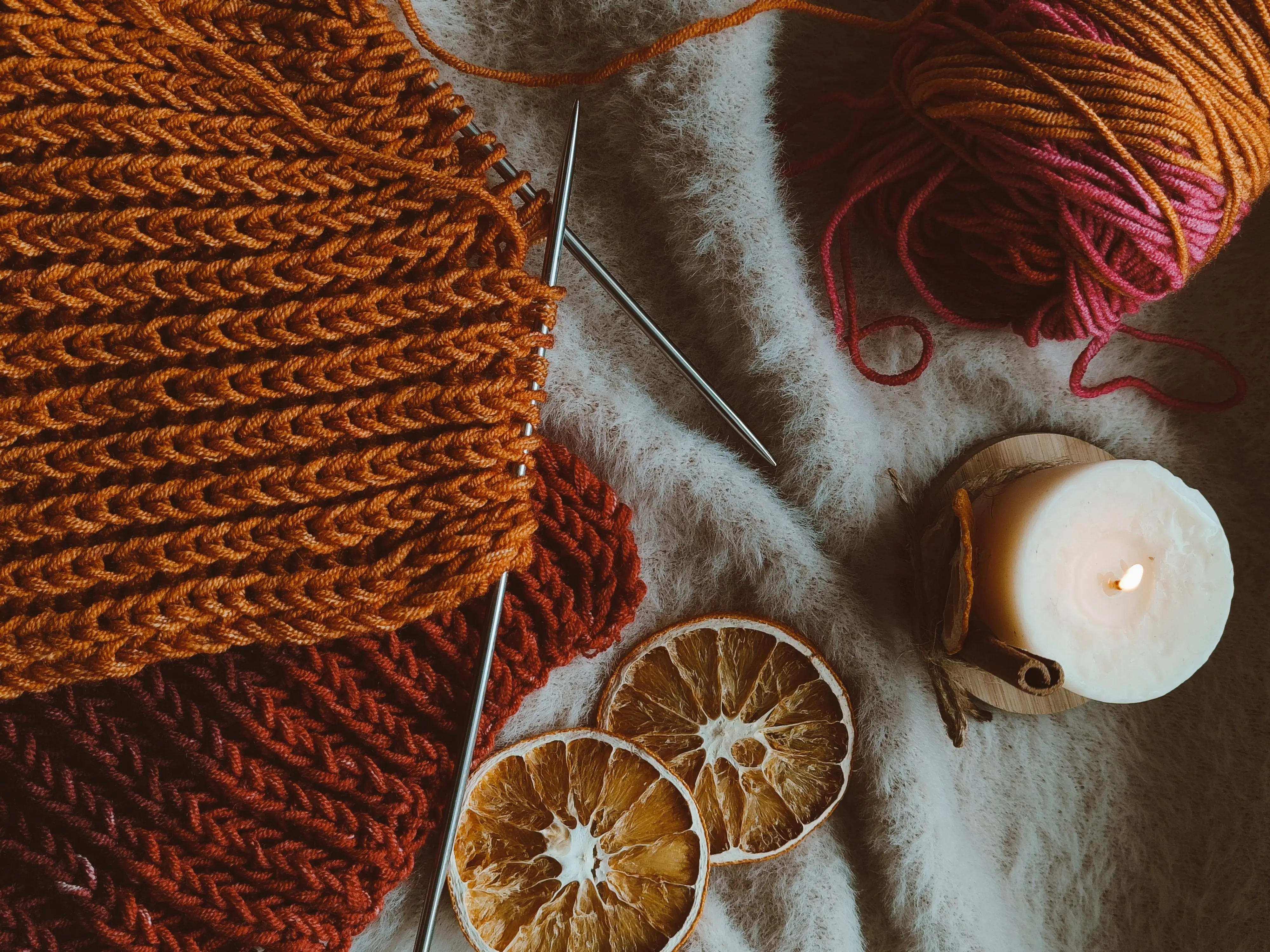 christmas craft kits Warm knitted fabric with yarn, knitting needles, candle, and dried oranges on soft fur.
