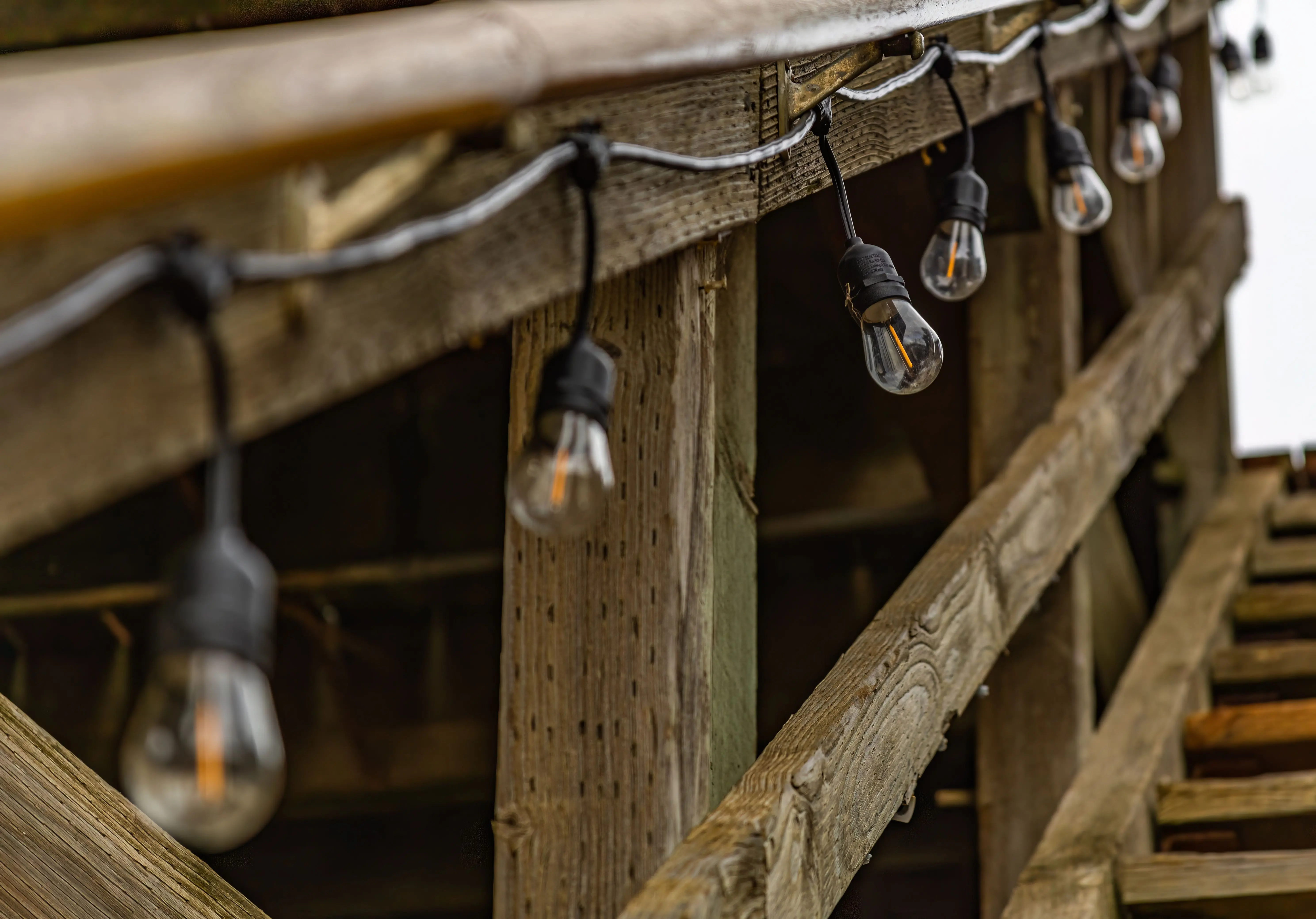 deck post lights Close-up of rustic wooden structure with string lights, creating a warm ambiance.