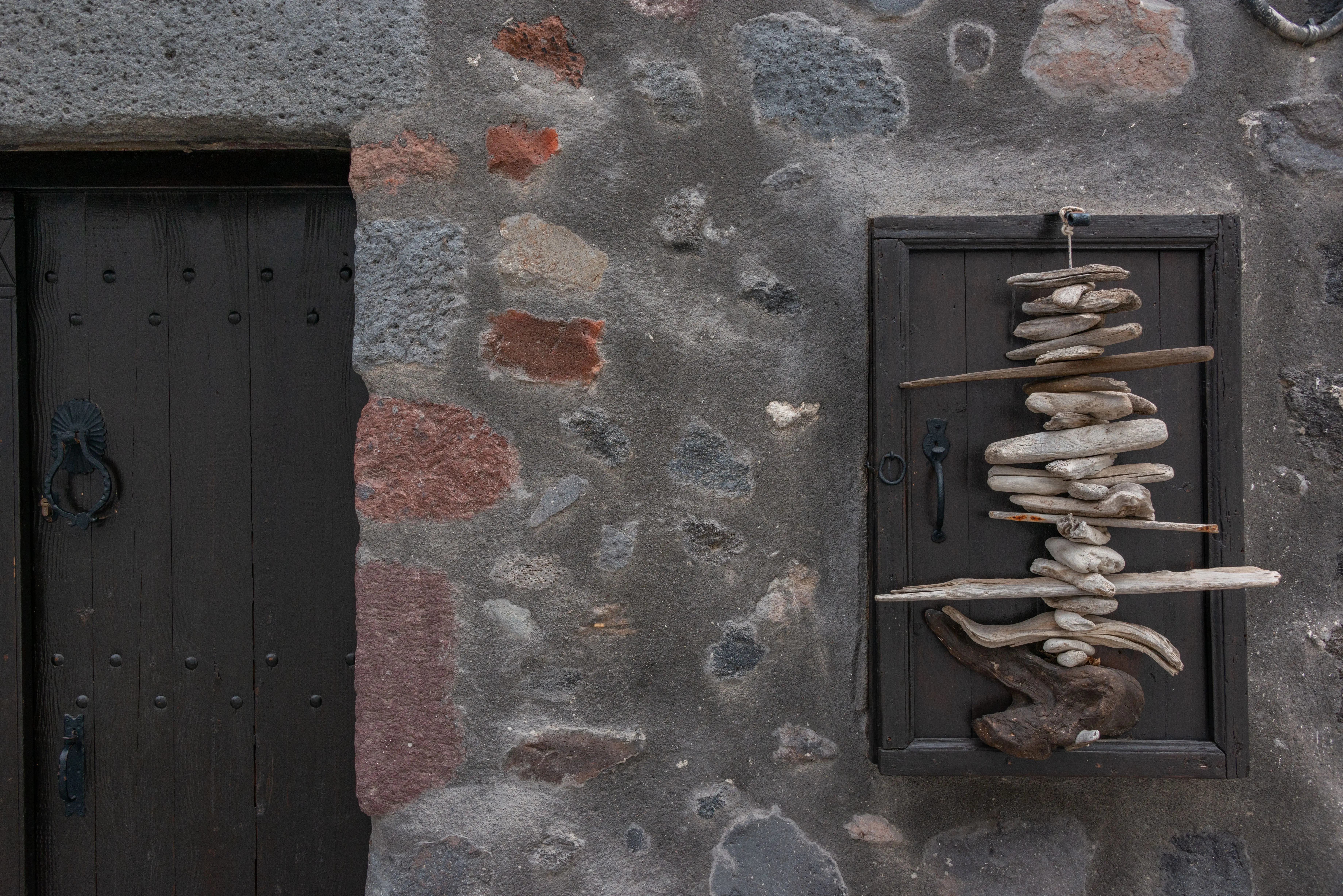 coastal wall decor Stone wall with a wooden door and driftwood sculpture in a rustic setting.
