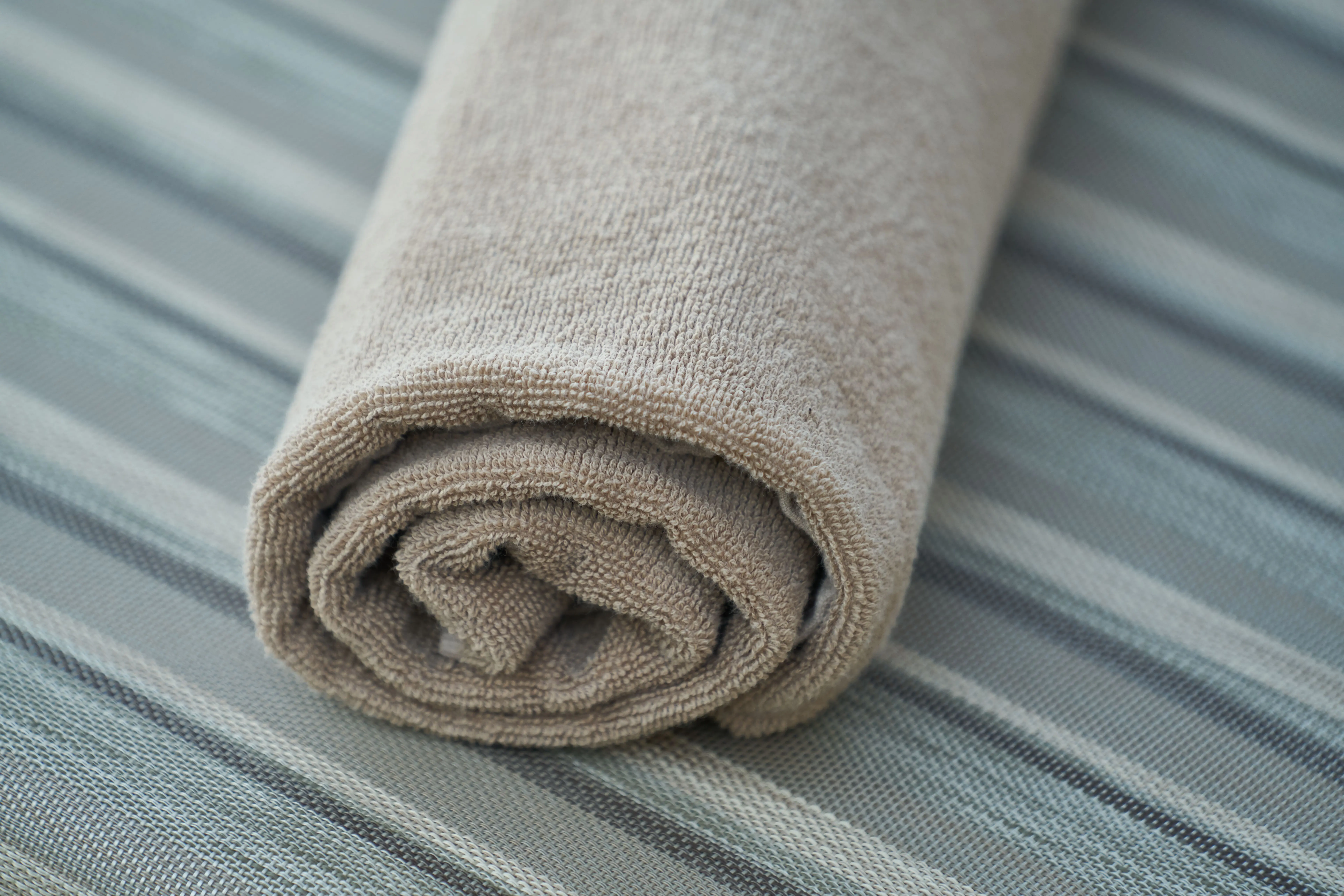 and paper towels Close-up of a soft beige cotton towel rolled neatly on a striped fabric surface. Perfect for home decor or textile themes.