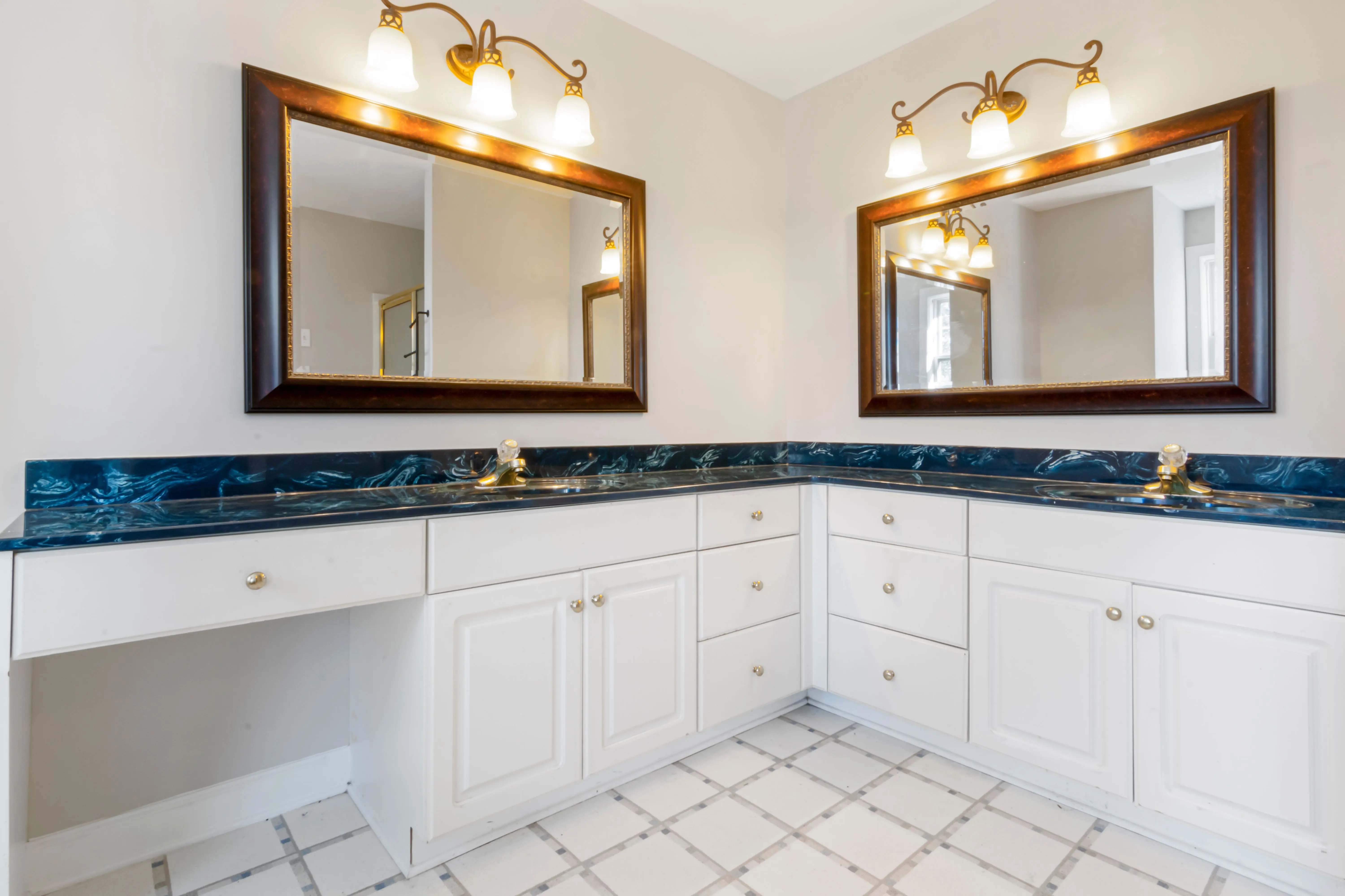 under sink cabinet Spacious bathroom with dual mirrors, elegant lighting, and modern countertop design.